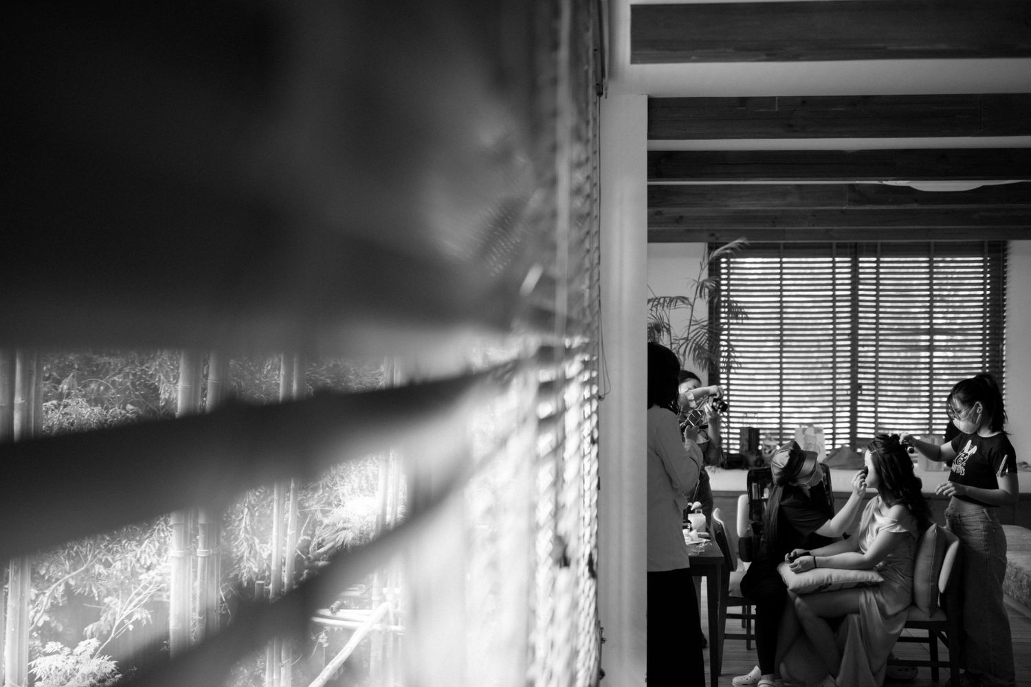Black and white photo of dramatic window light casting shadows through venetian blinds.