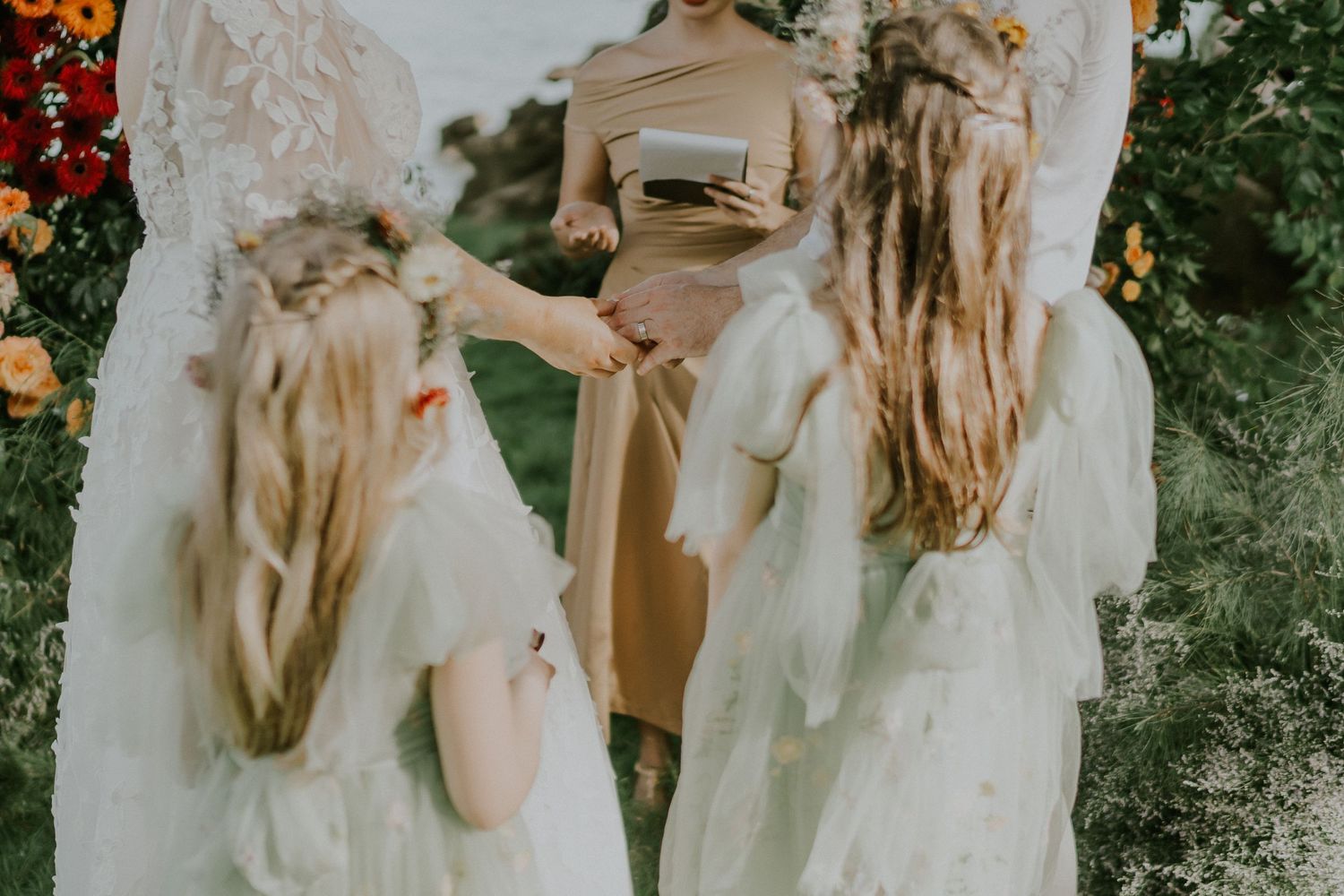 Wedding party in white dresses gathered during outdoor ceremony.