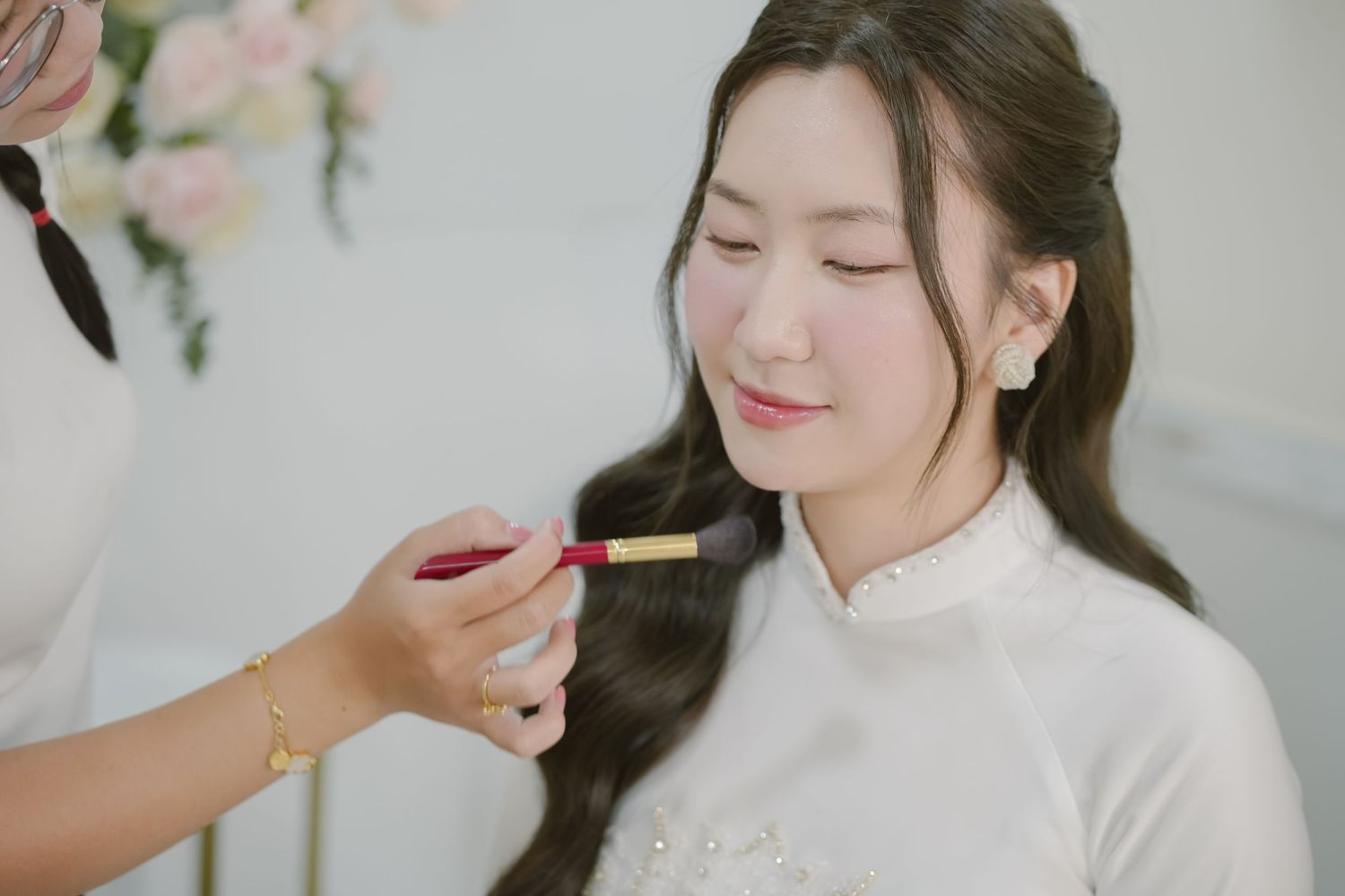 A gentle makeup application moment captured during wedding preparations.