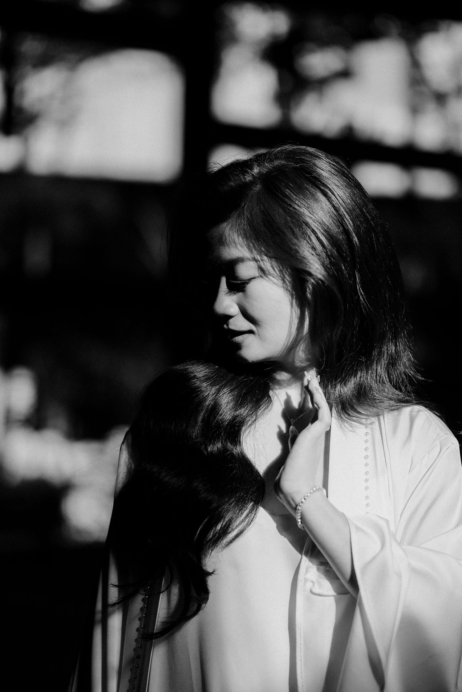 Artistic black and white portrait of a woman in soft natural lighting.