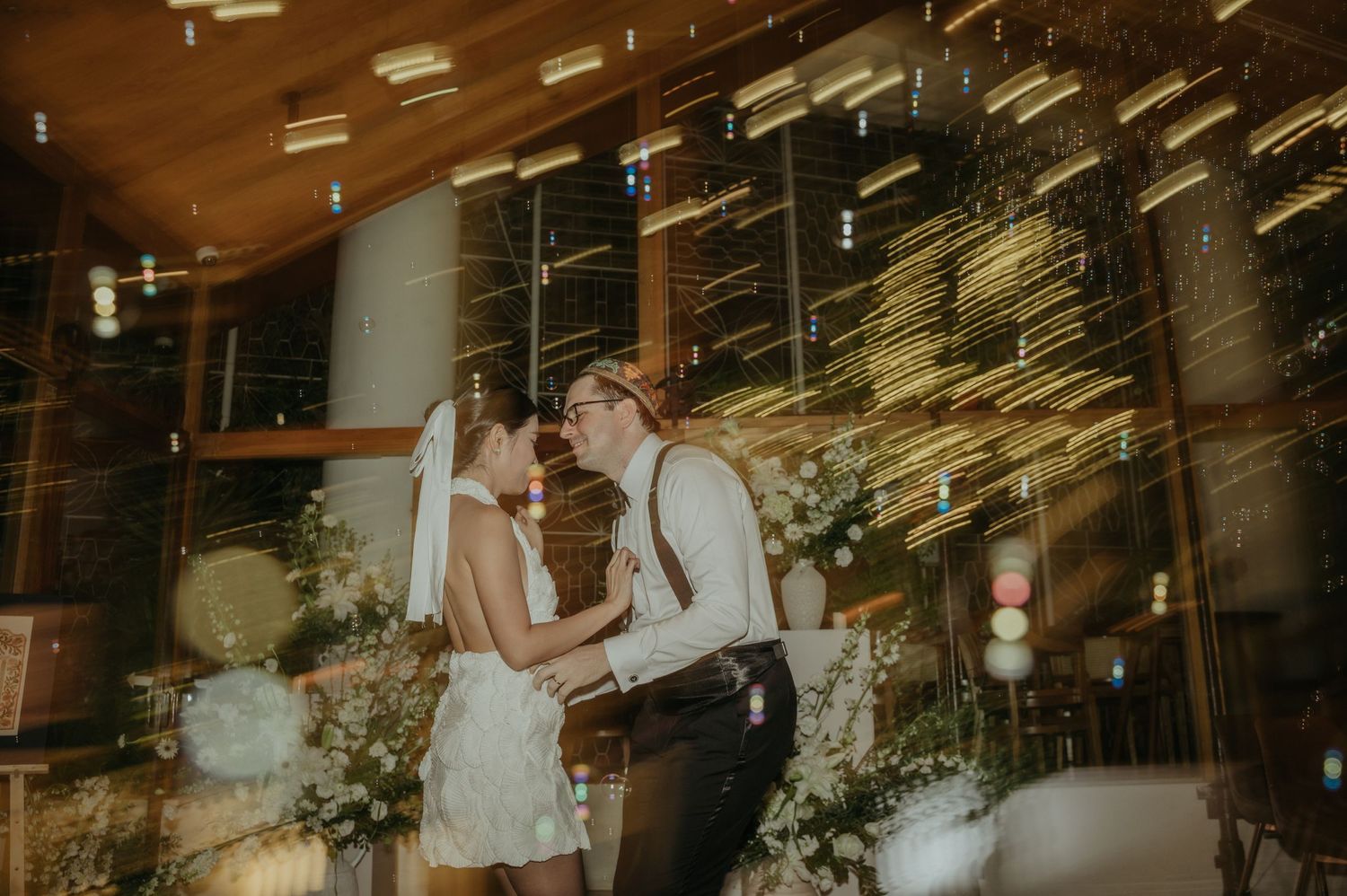 Couple sharing an intimate dance moment under glittering ceiling lights.