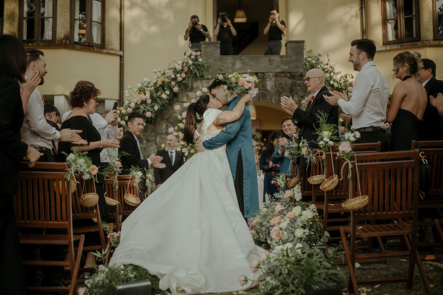 Romantic wedding ceremony in a chapel decorated with lush white and green floral arrangements along wooden pews.