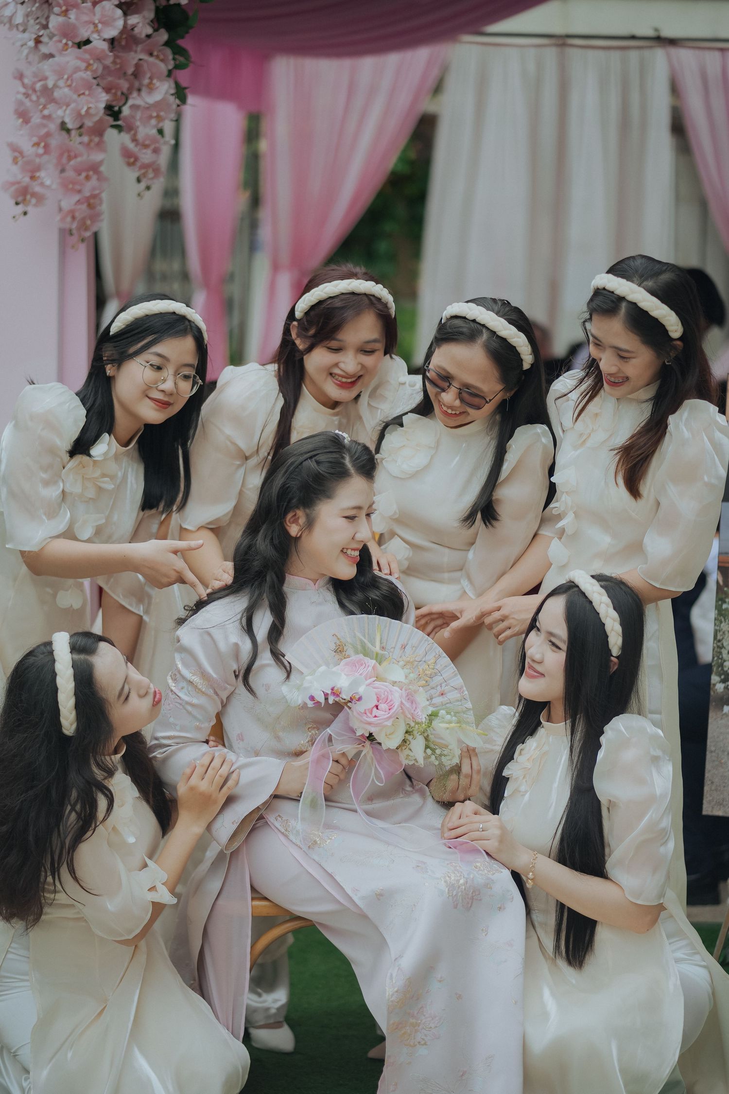 Bridesmaids in white ao dai dresses gather together during traditional Vietnamese wedding celebration.