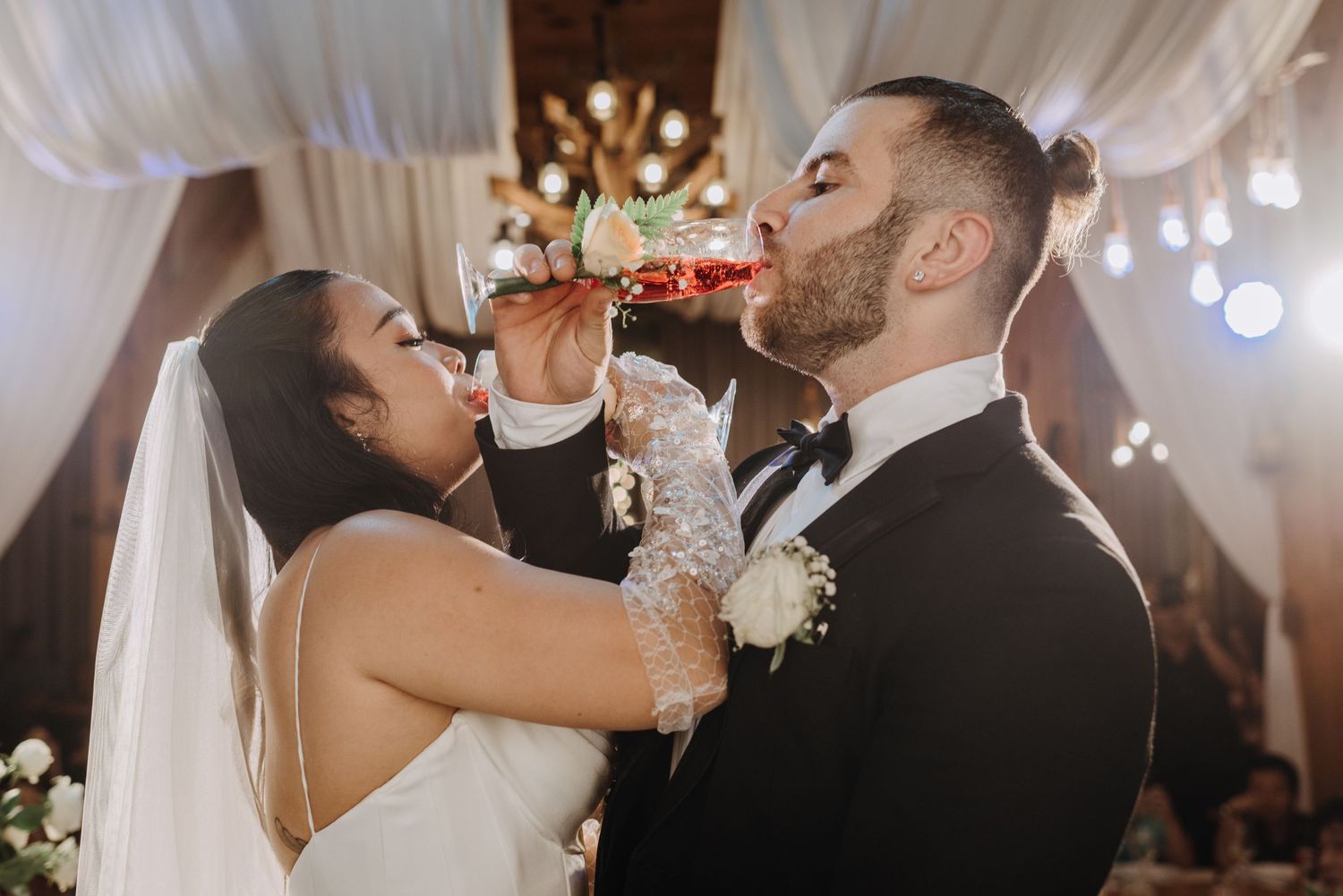 A celebratory moment shows newlyweds sharing a drink during their wedding reception.