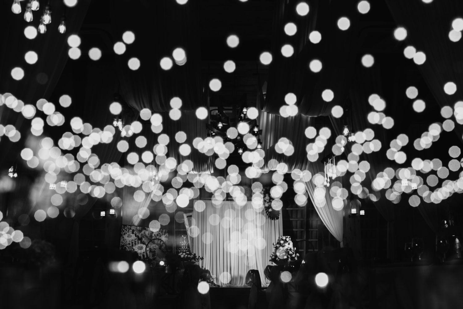 Black and white image of bokeh lights creating a magical atmosphere at a wedding venue.