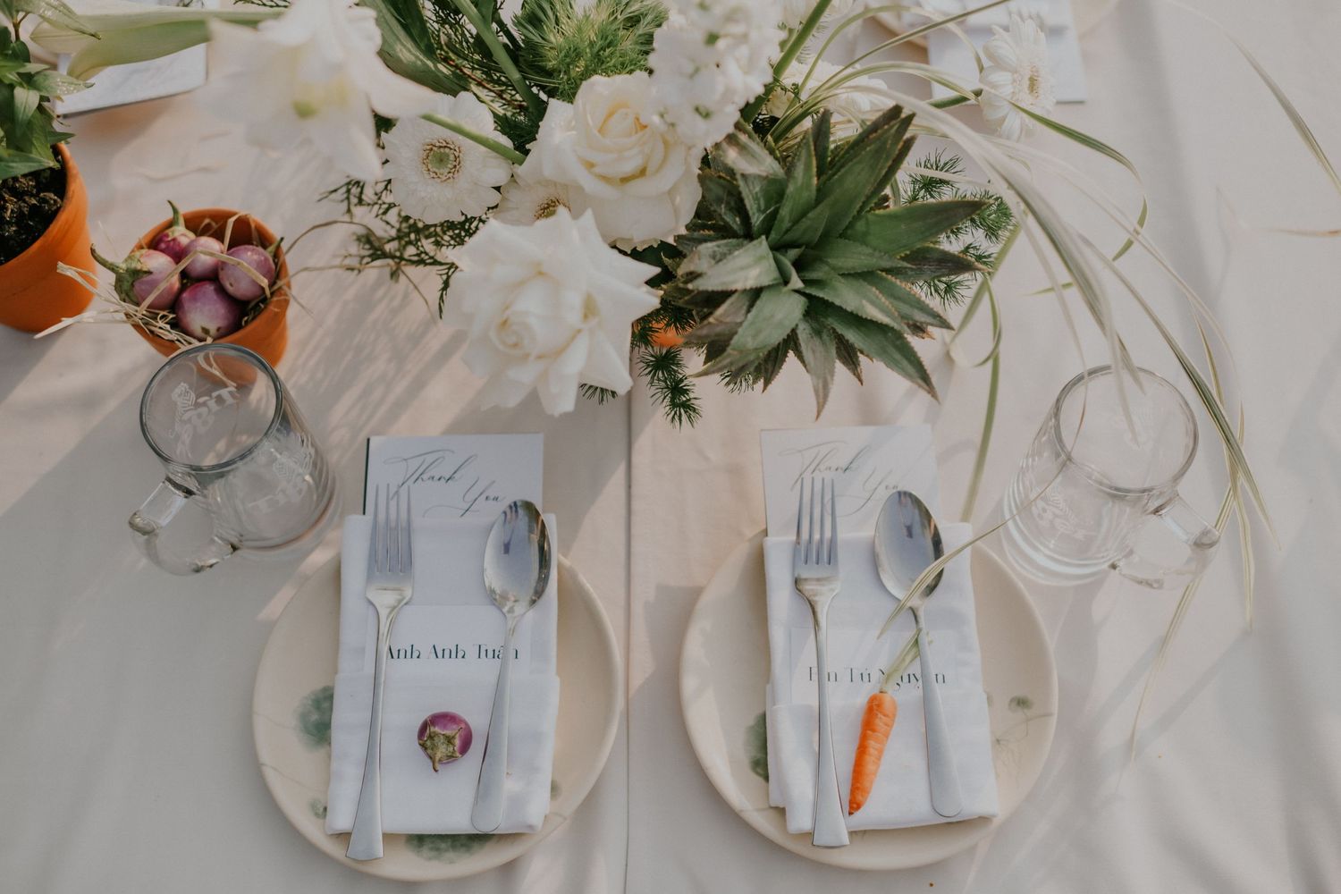 Elegant table settings with succulent centerpieces and white floral arrangements on white linens.
