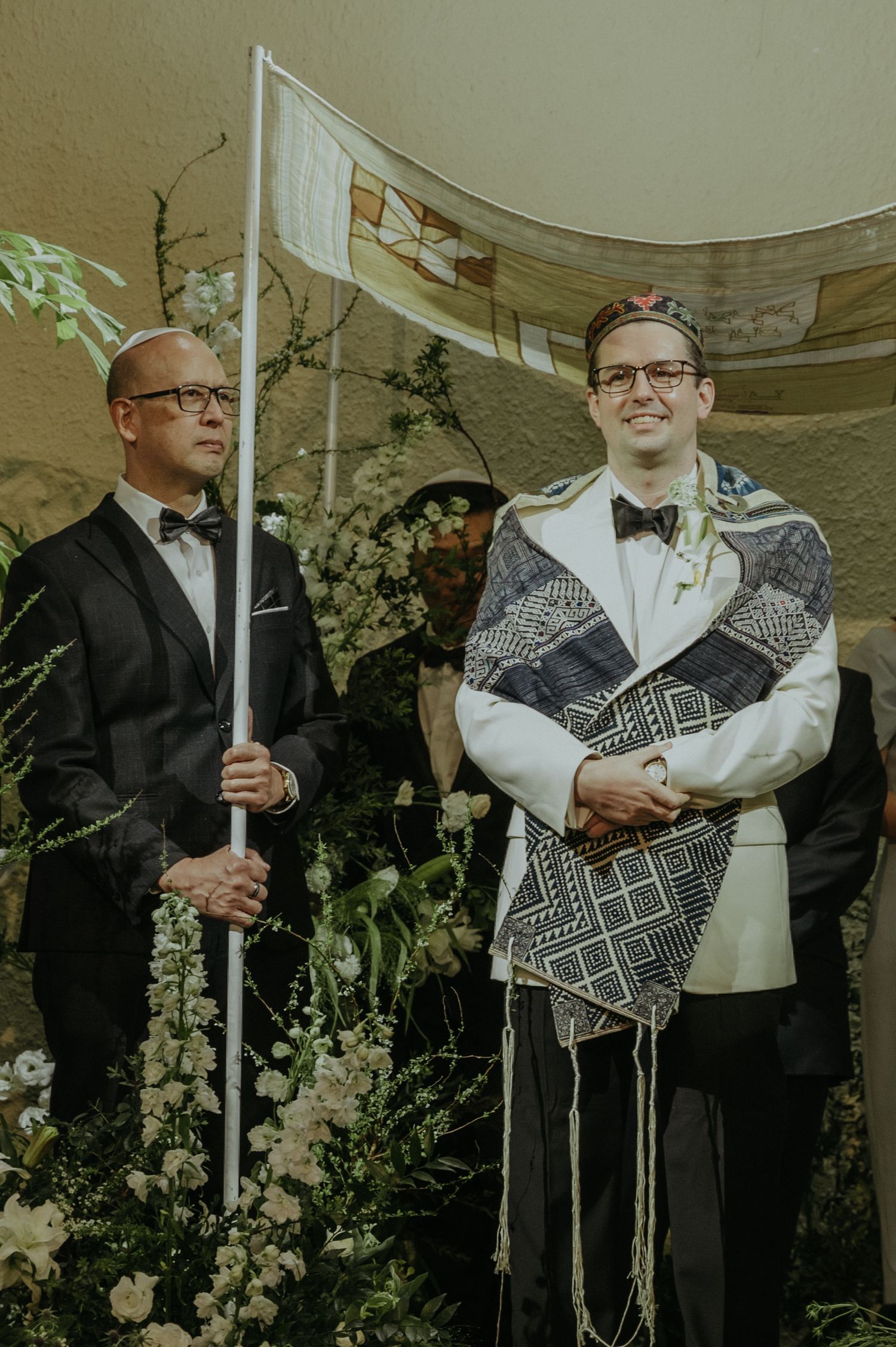 Two attendants stand at ceremony altar with one holding a ceremonial pole.