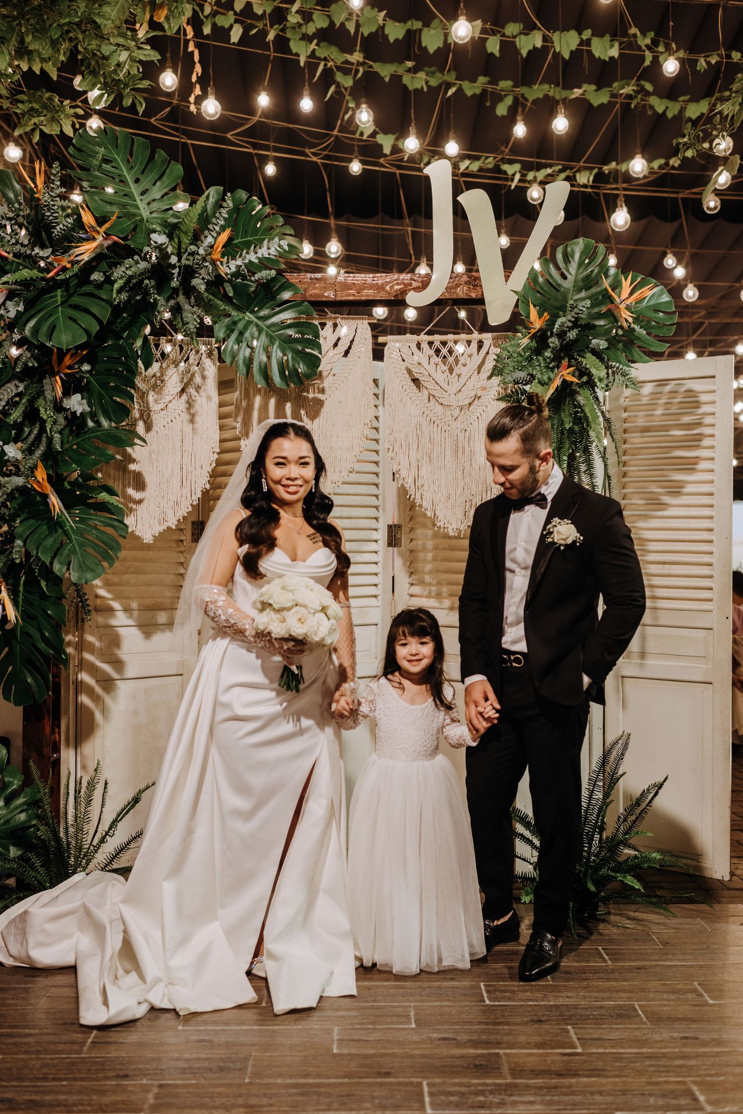 Wedding ceremony setup with tropical decor, string lights, and macrame backdrop.