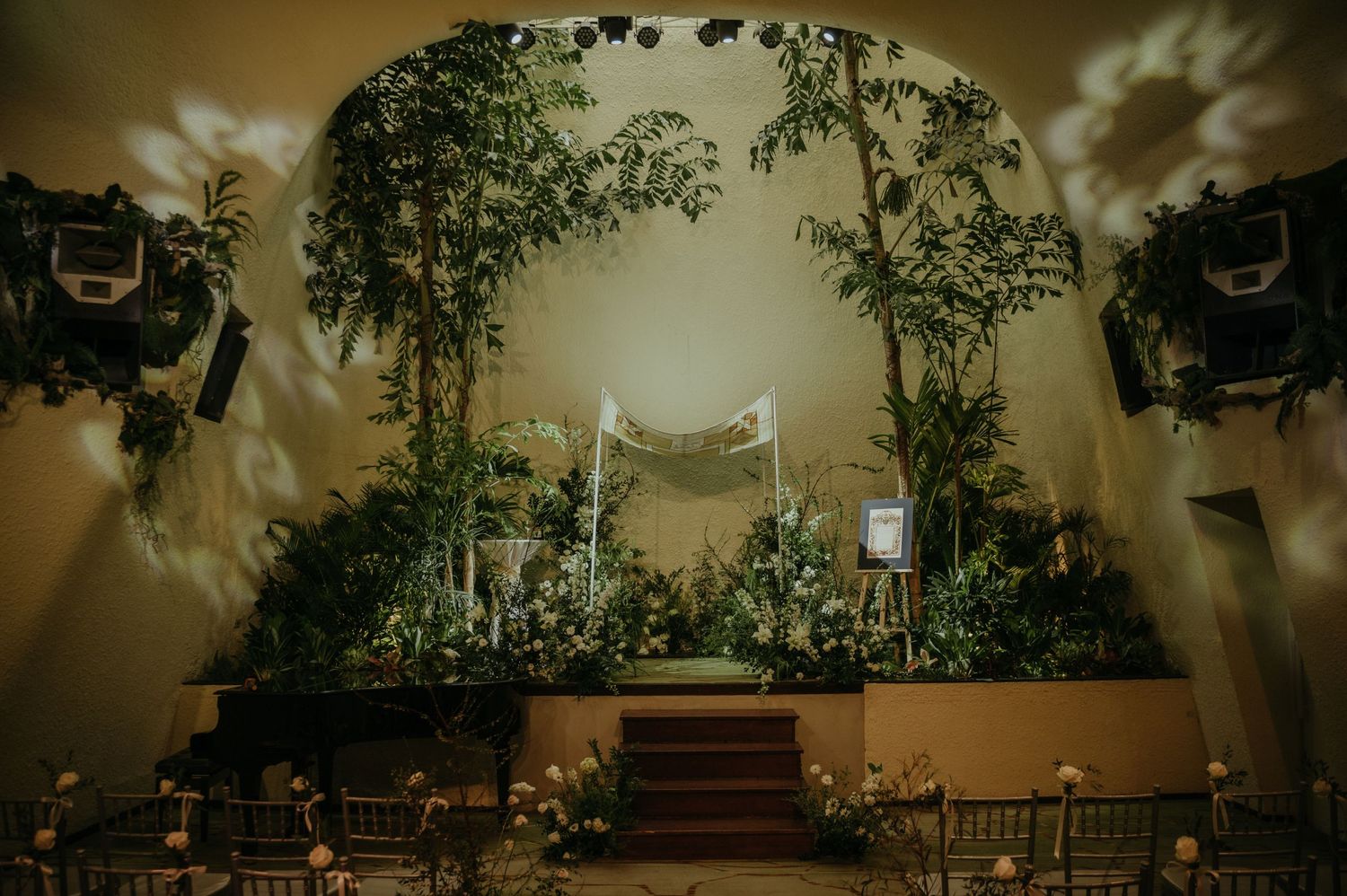 Atmospheric wedding venue with arched ceiling, draped fabric and dramatic lighting.
