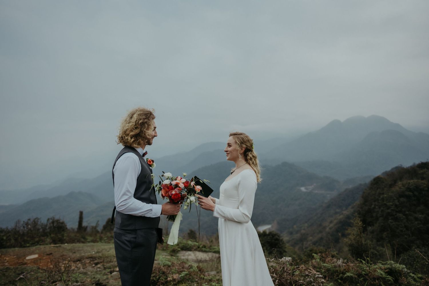 Mountain wedding ceremony with couple toasting against misty mountain backdrop.