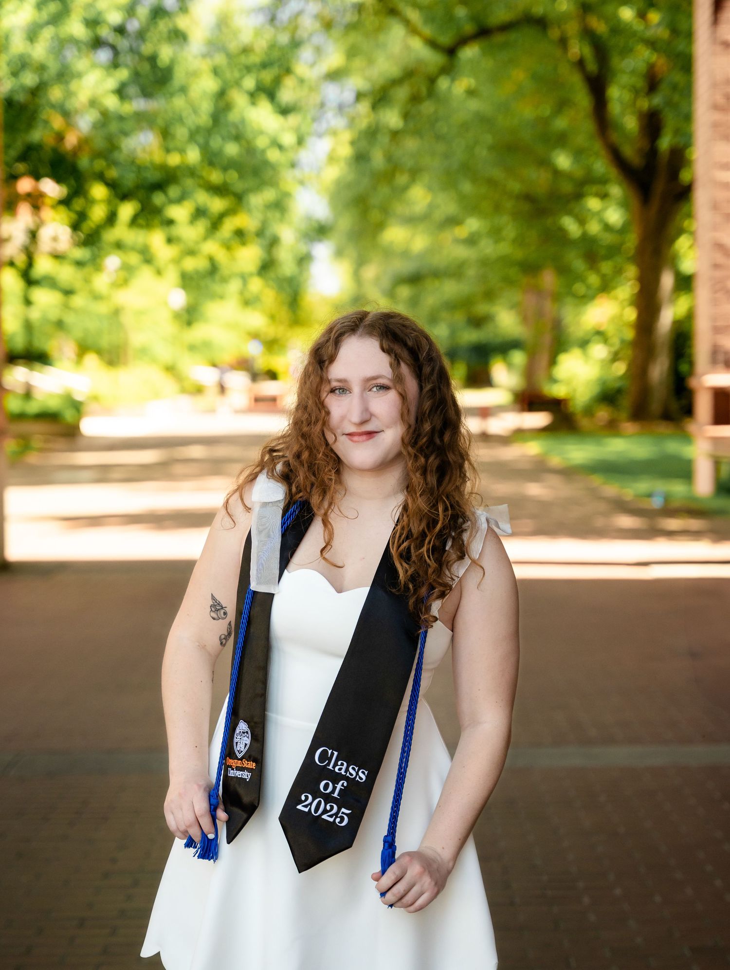 A series of portrait photos showing someone in white graduation attire smiling while standing under an outdoor pavilion.