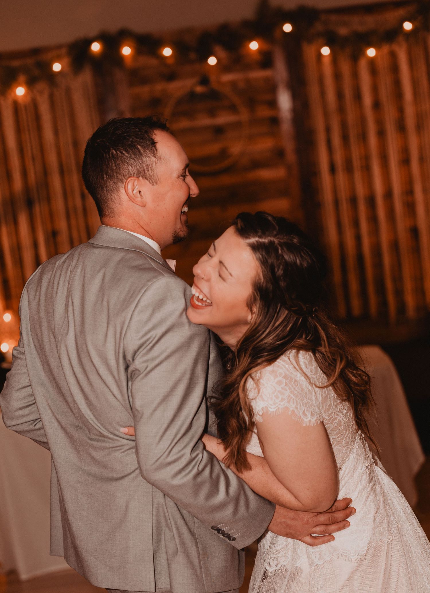 A couple dancing together at a rustic barn wedding reception with string lights creating a warm atmosphere.