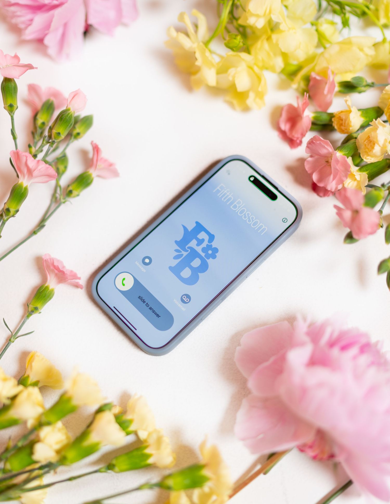 Pink carnations and yellow flowers surround a smartphone displaying a social media app interface on white background.