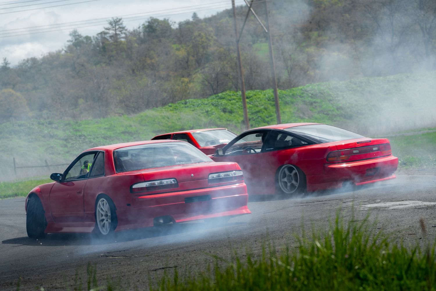 Red sports car performing a high-speed drift on a wet road creating dramatic smoke and spray.