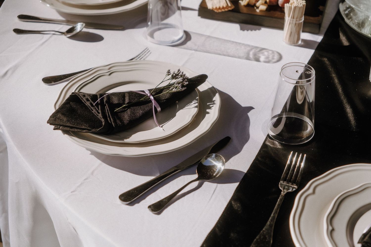 Formal place setting with white plates and silverware on crisp white tablecloth.