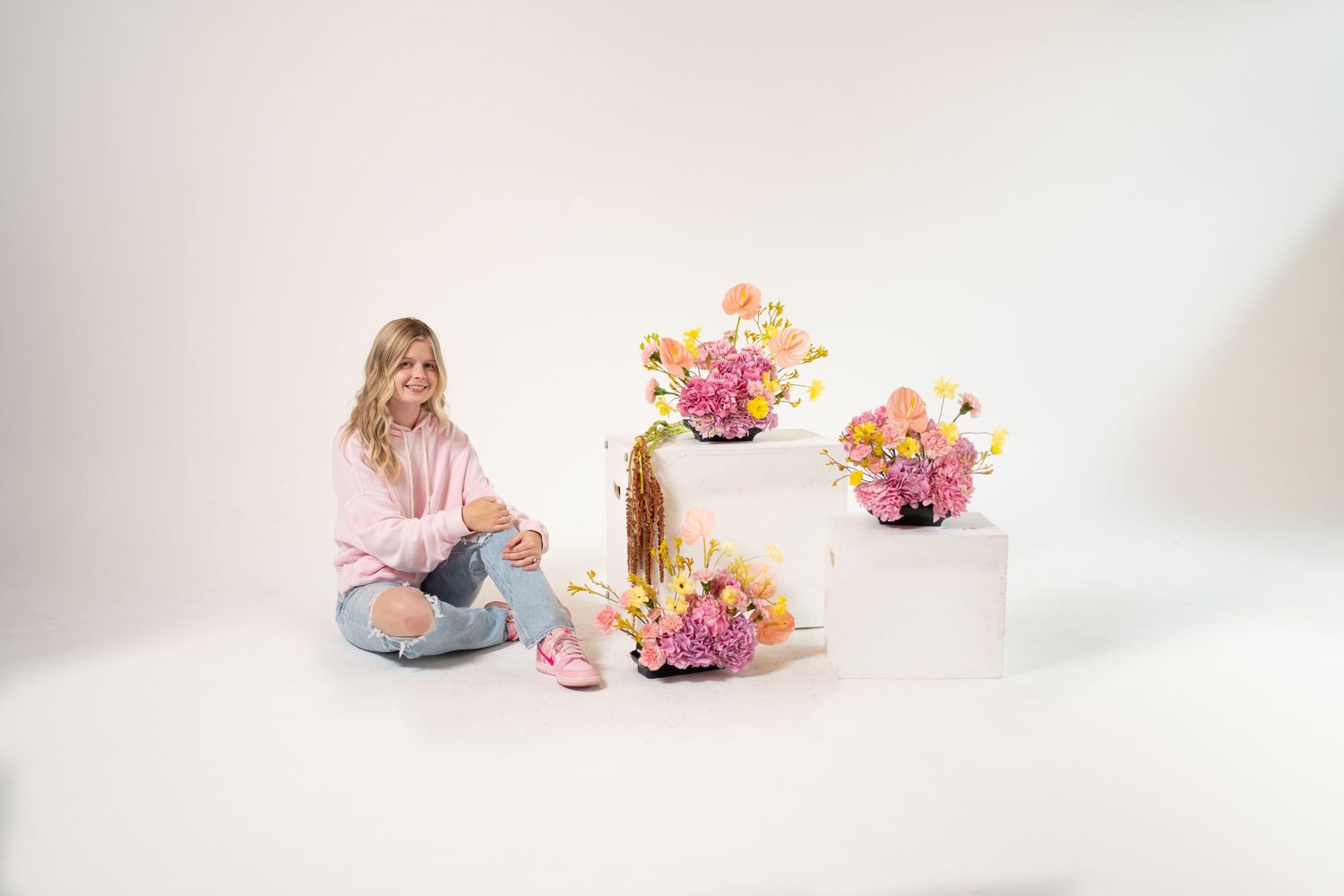 White porcelain vases with pink and yellow flowers arranged against a bright white minimalist background.
