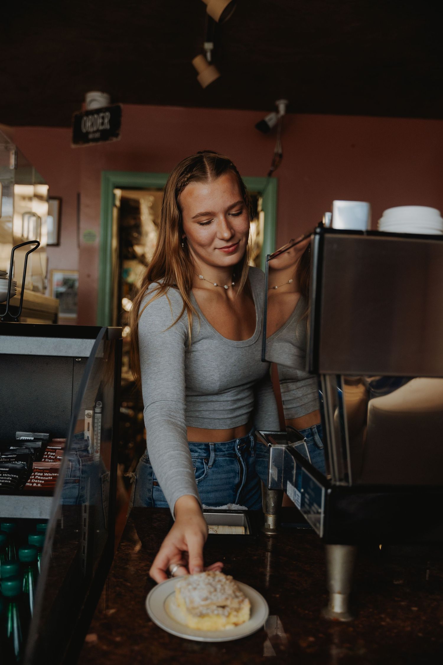Cafe worker serving a fresh plate of food at counter.