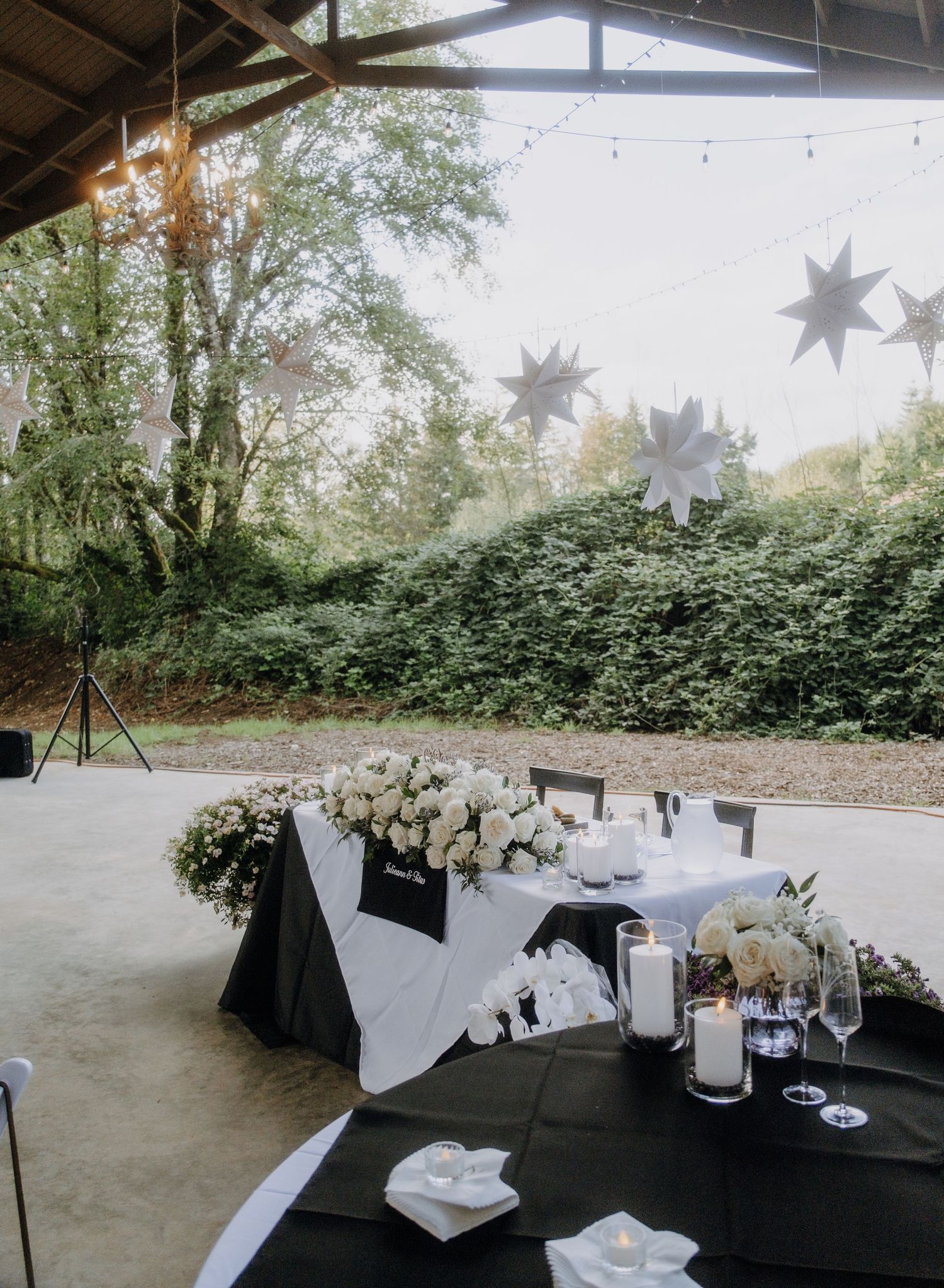 A series of outdoor event spaces with white decor and string lights hanging overhead create an elegant reception atmosphere.