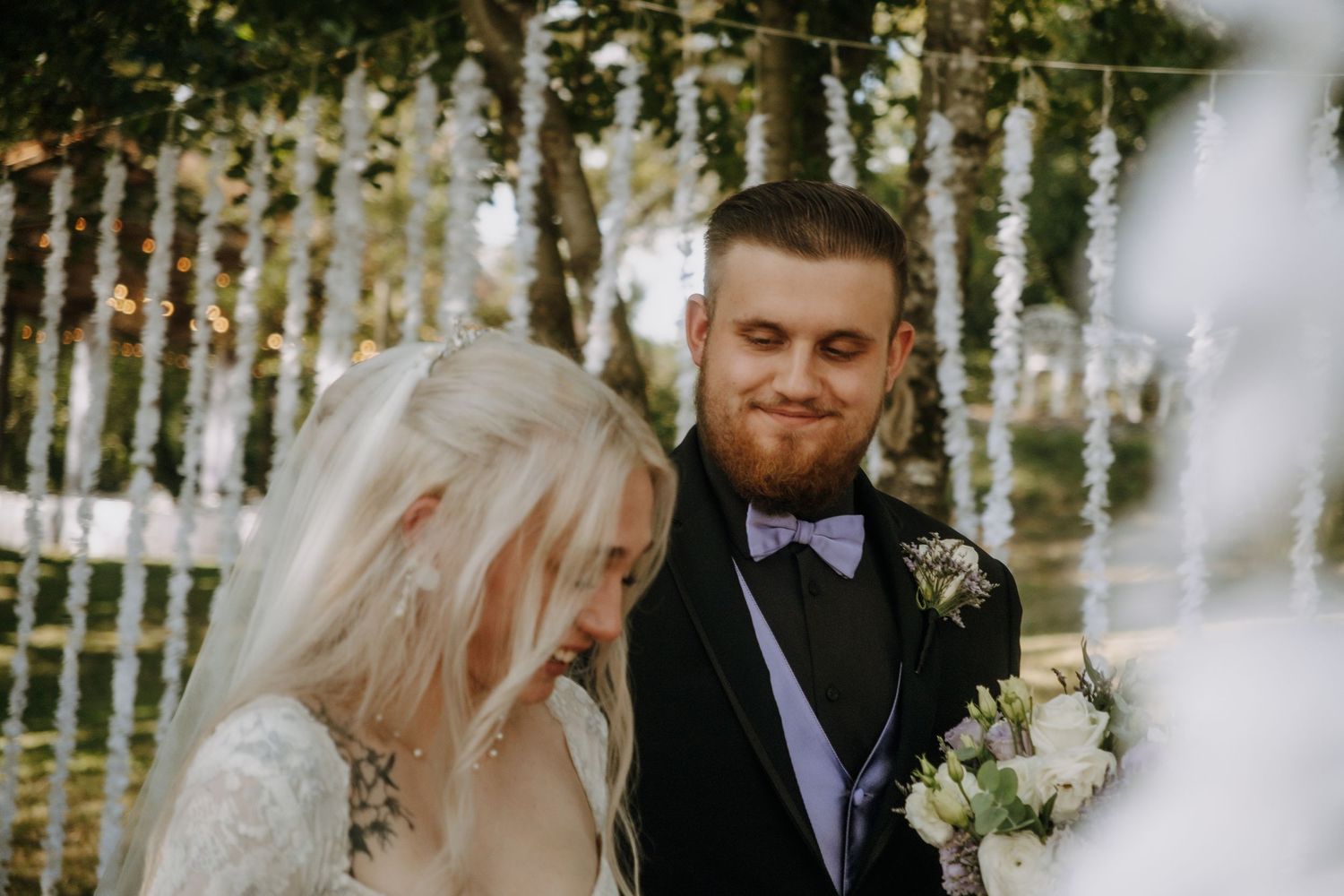 Intimate wedding ceremony moment between couple under decorative outdoor lighting.