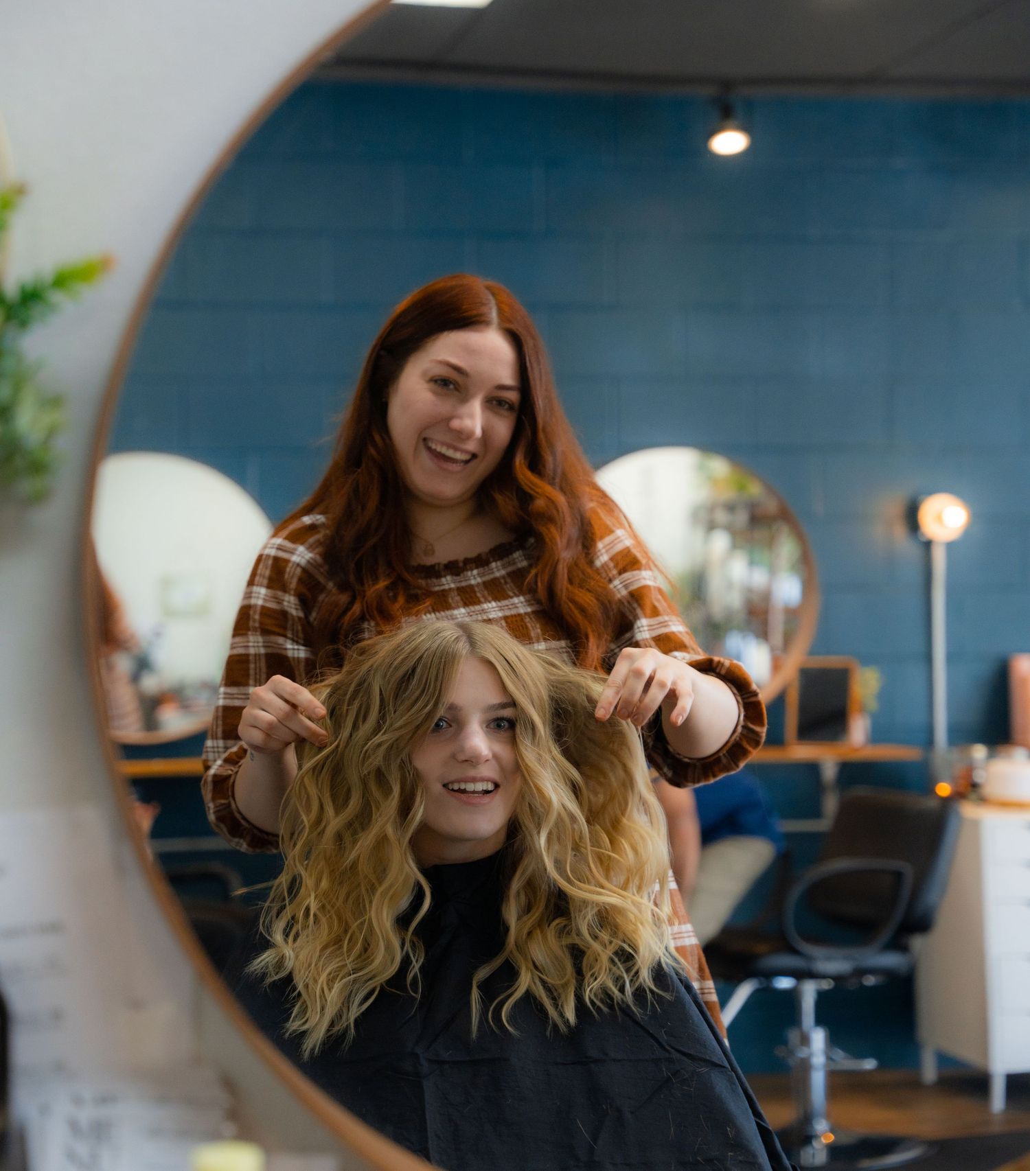 Stylish interior of hair salon with blue walls and round mirror.