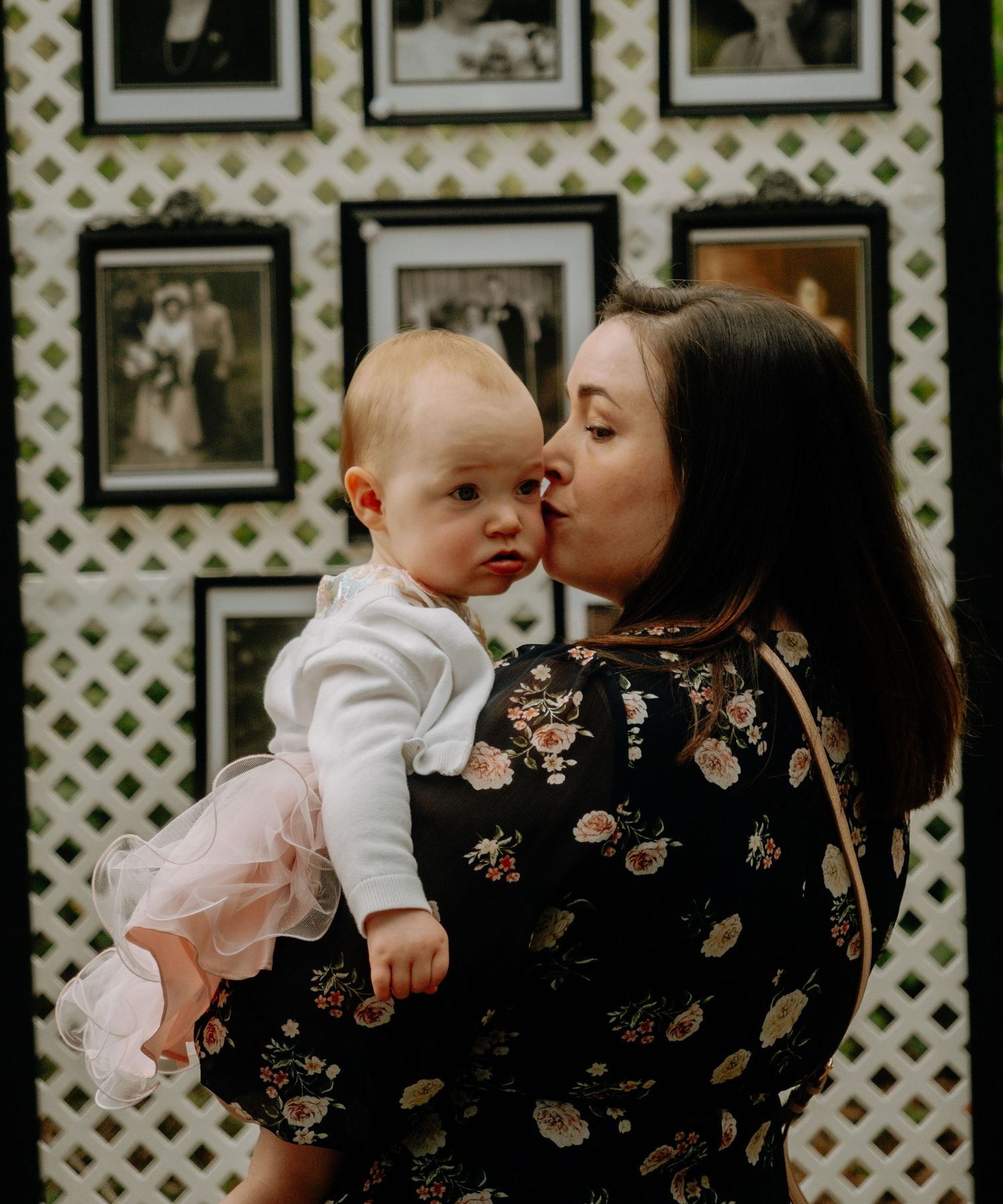 Sweet family moment captured against wall of vintage framed photographs.