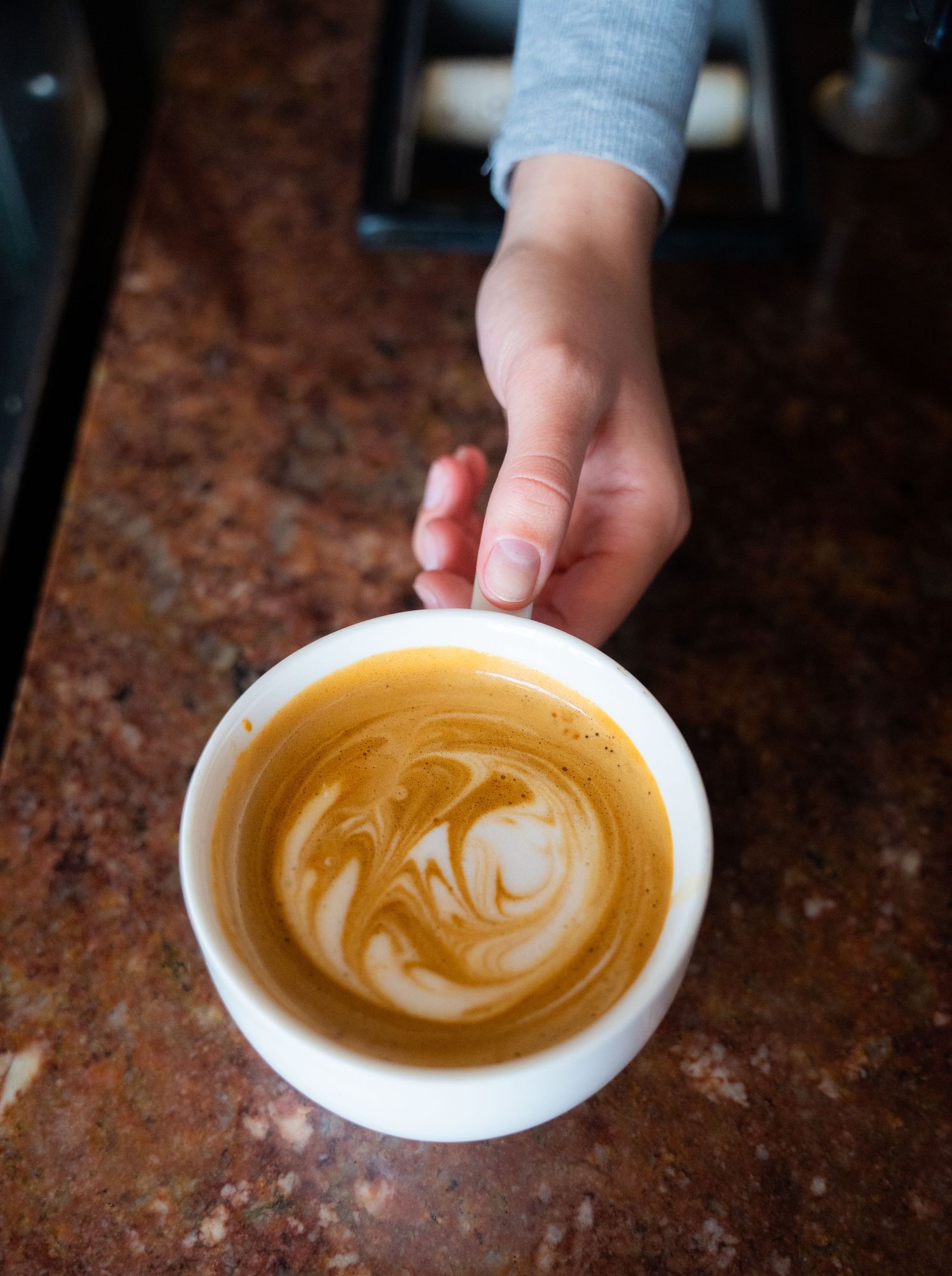 Close-up of latte art showing swirled heart design in coffee cup.