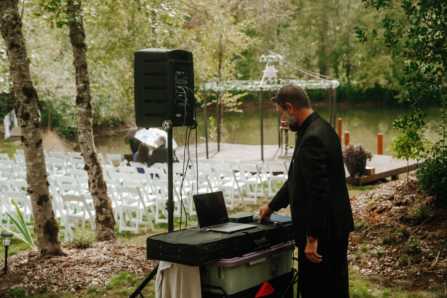 A musician playing piano at an outdoor wedding ceremony in a wooded setting.