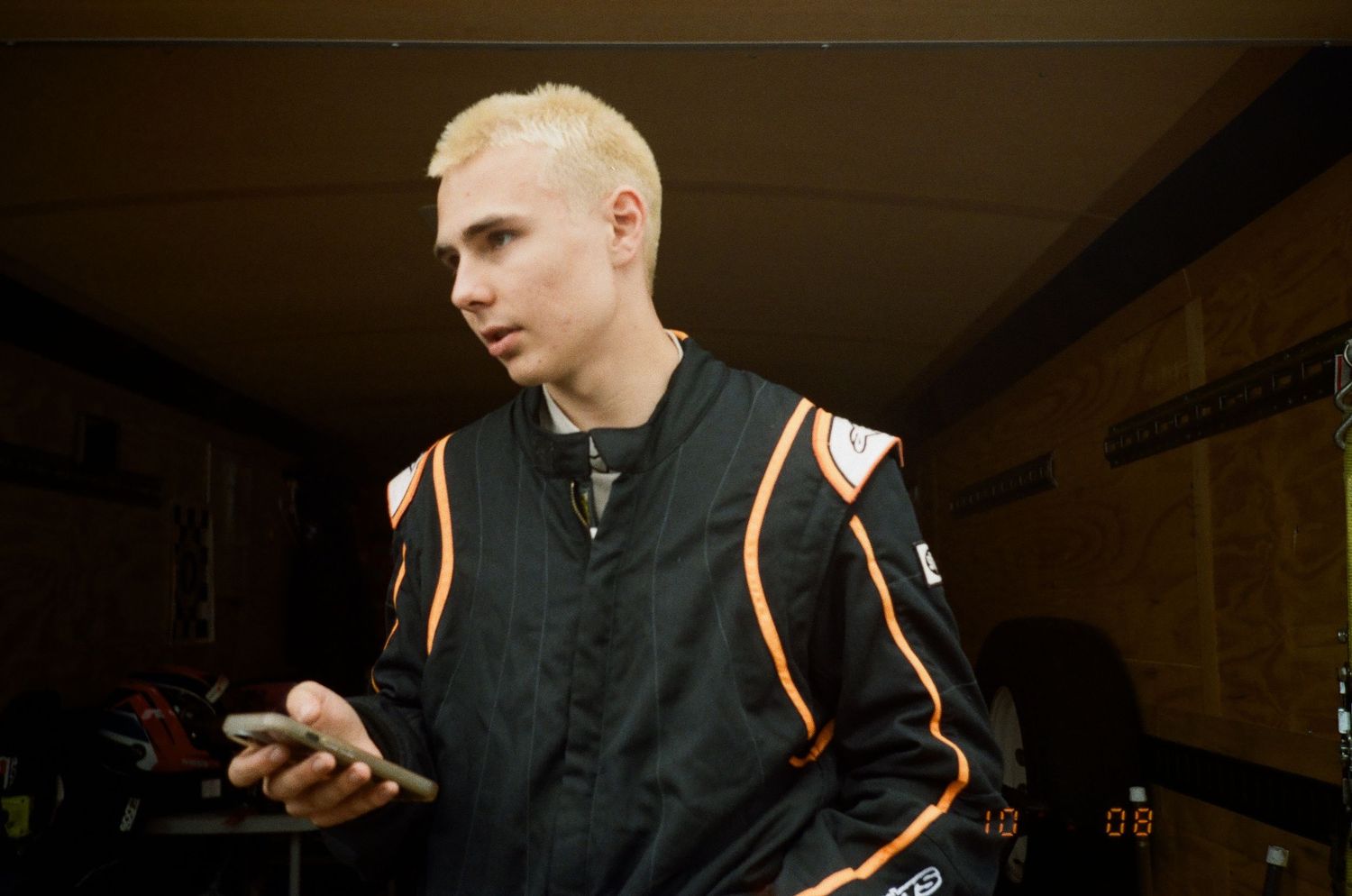 A figure in black clothing and orange accents plays with objects at a dimly lit event.