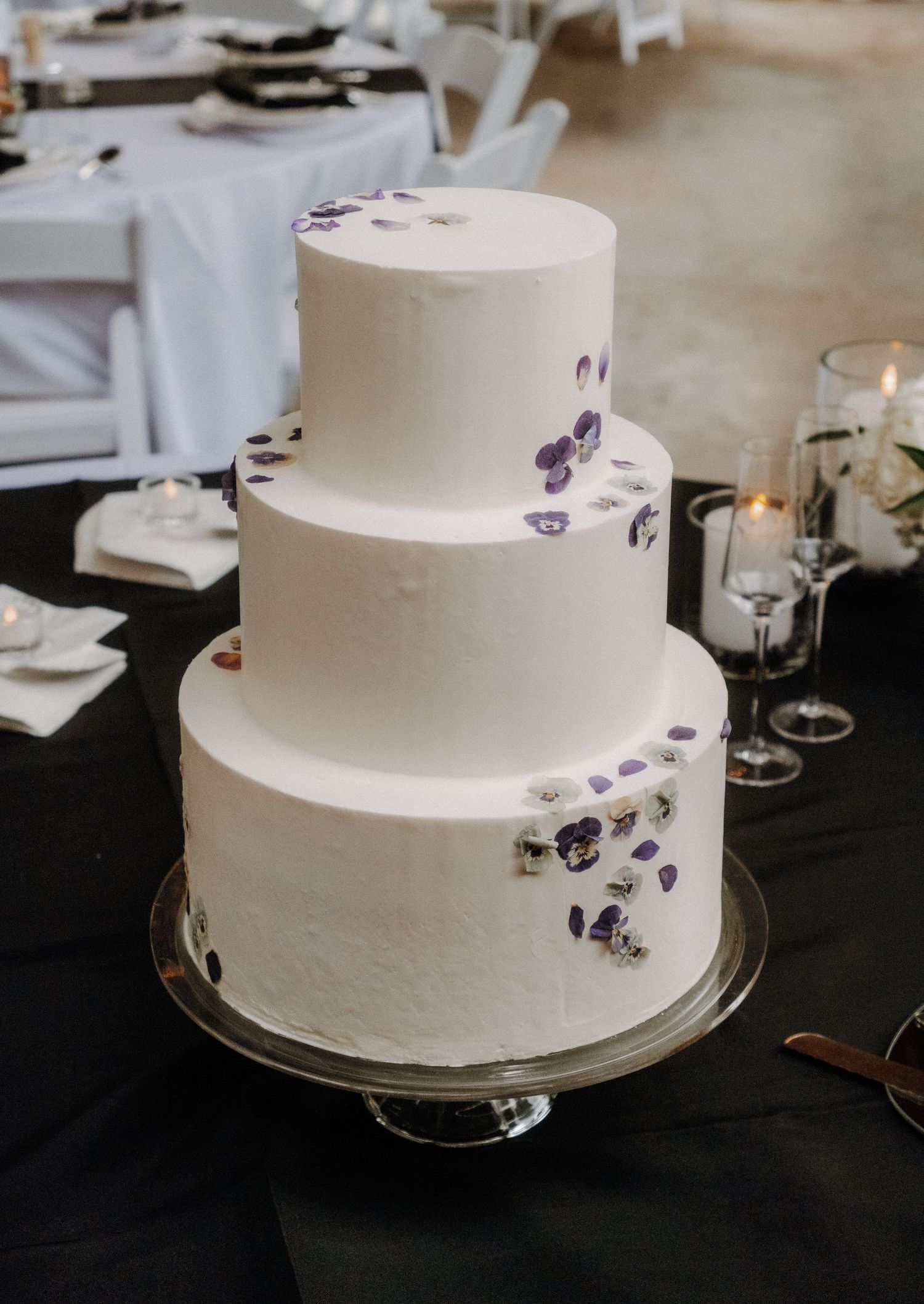 A classic three-tiered white wedding cake decorated with delicate purple flower accents.