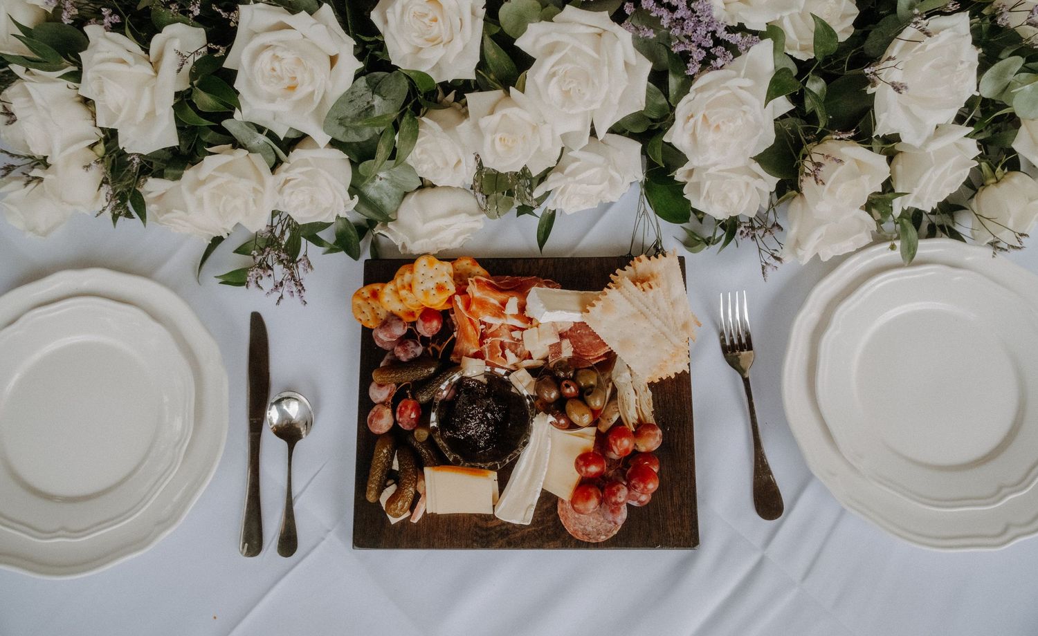 An elegant white table setting at a wedding reception with floral centerpieces and place settings.