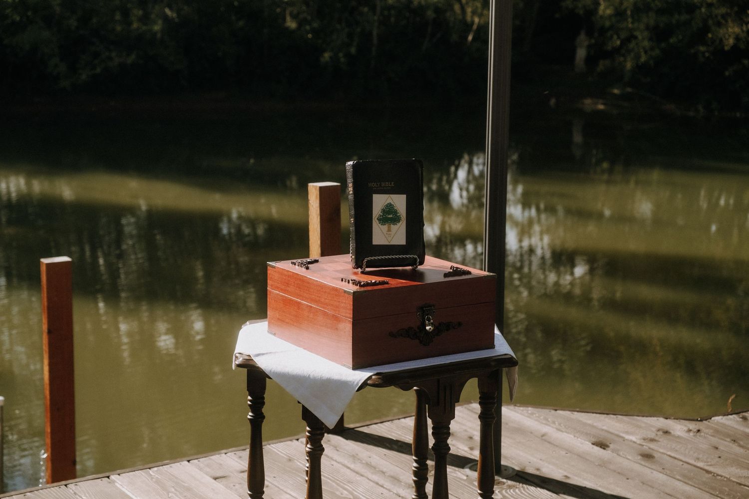 Vintage wooden box camera displayed on small table by a pond.