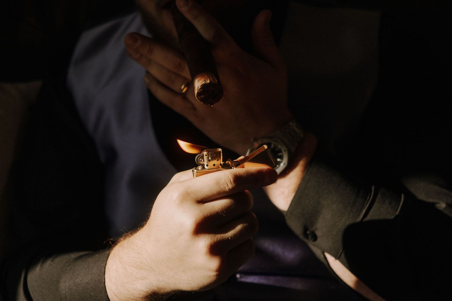 Close-up of hands adjusting cufflinks in dramatic lighting.