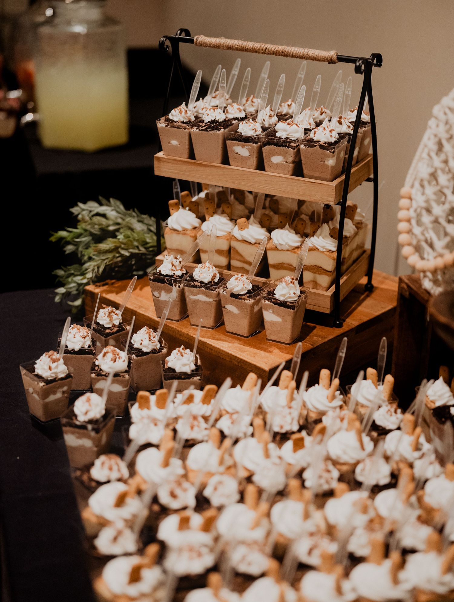 A tiered display of wedding desserts and treats arranged on a wooden stand with decorative flowers.