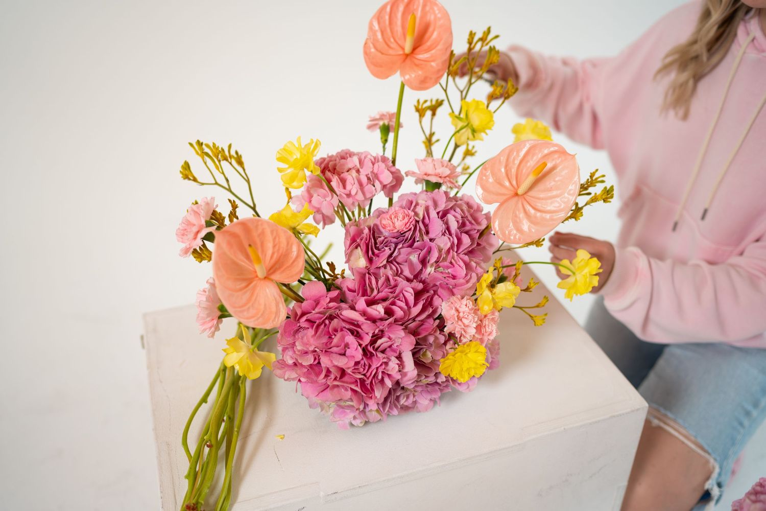 Close-up of pink and peach floral arrangement with carnations and yellow accent flowers.