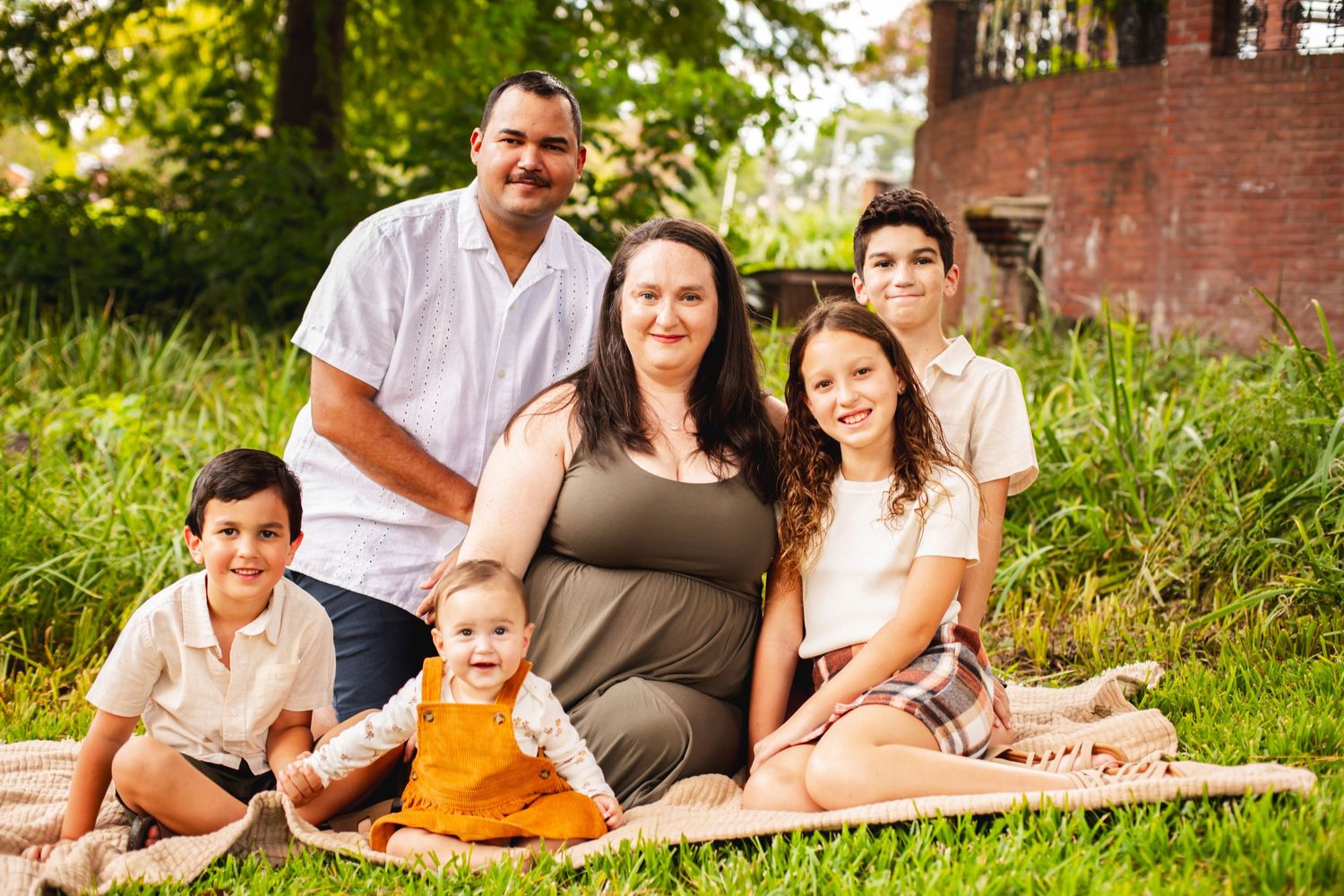 Family enjoying a relaxing picnic together on a blanket in a lush green outdoor setting.