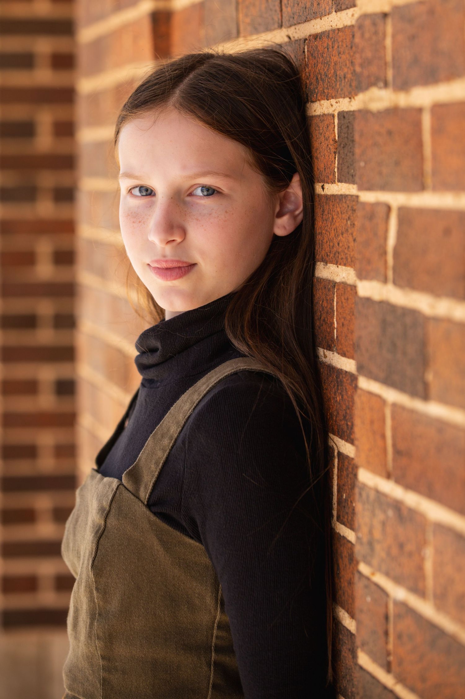 Portrait series against brick wall showing artistic angles and dramatic lighting.