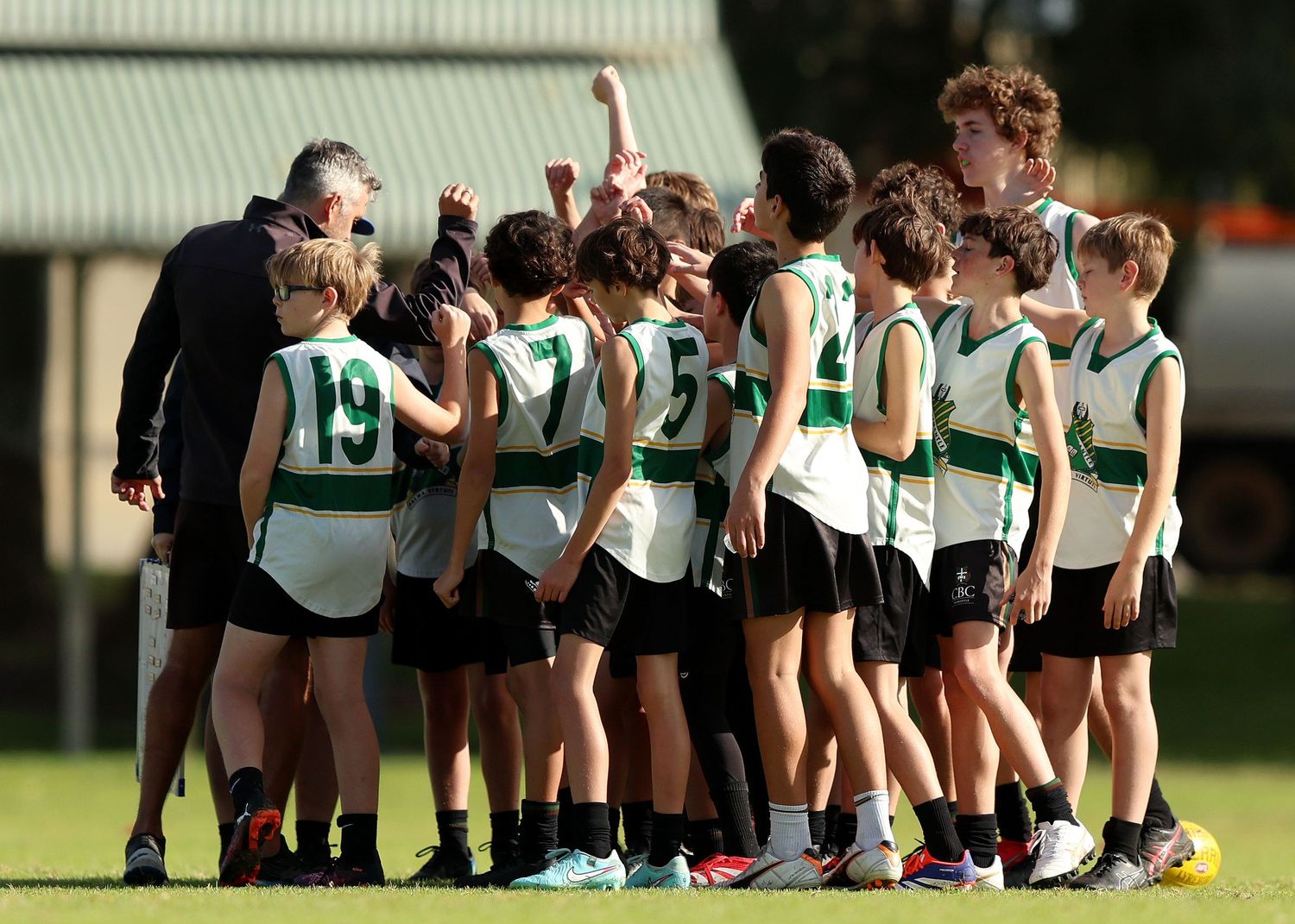 Soccer team players huddle together in a row on the grass field during a match or practice session.