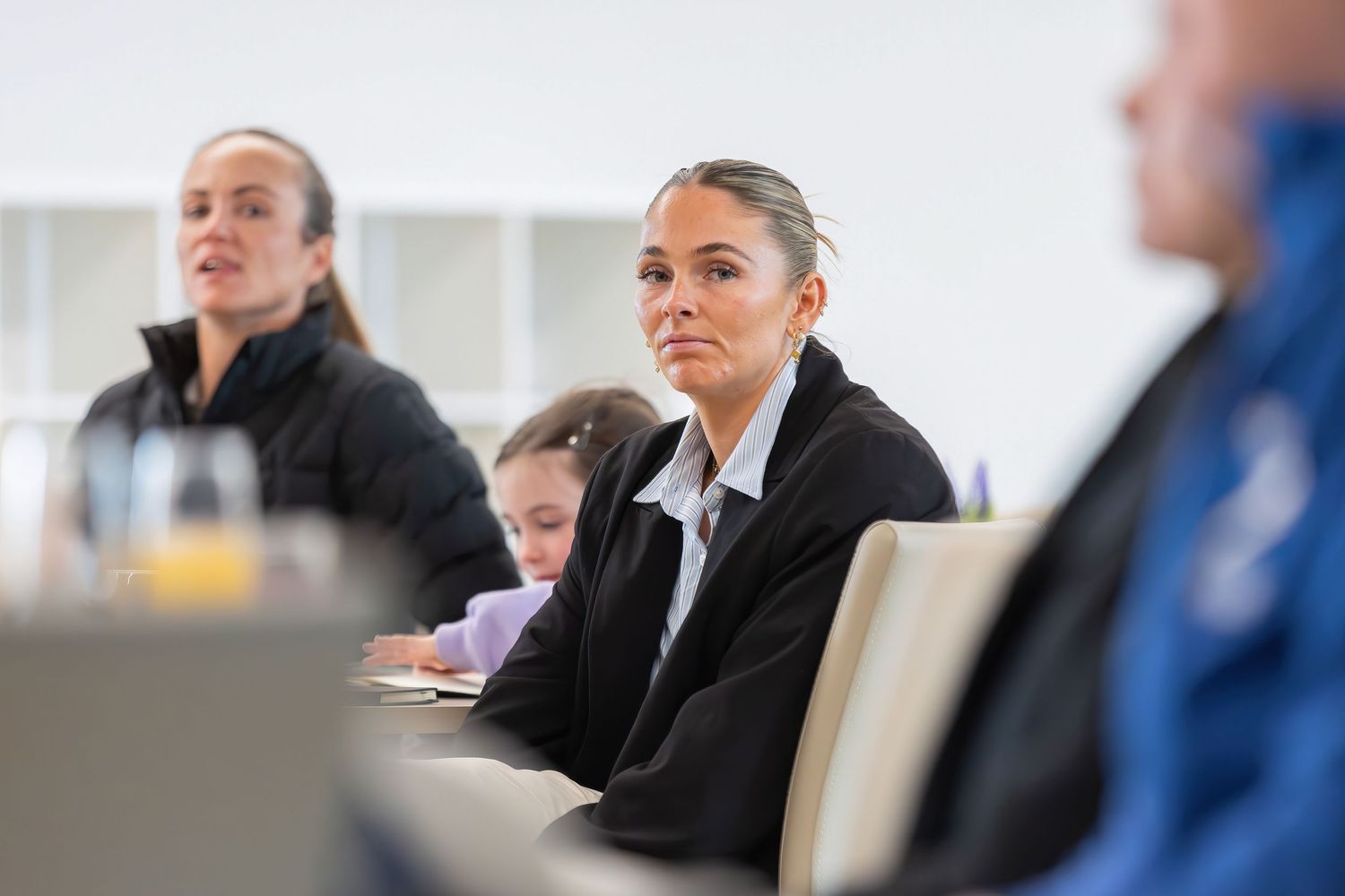 Professionals attend a business meeting in a conference room with drinks and notes on the table.