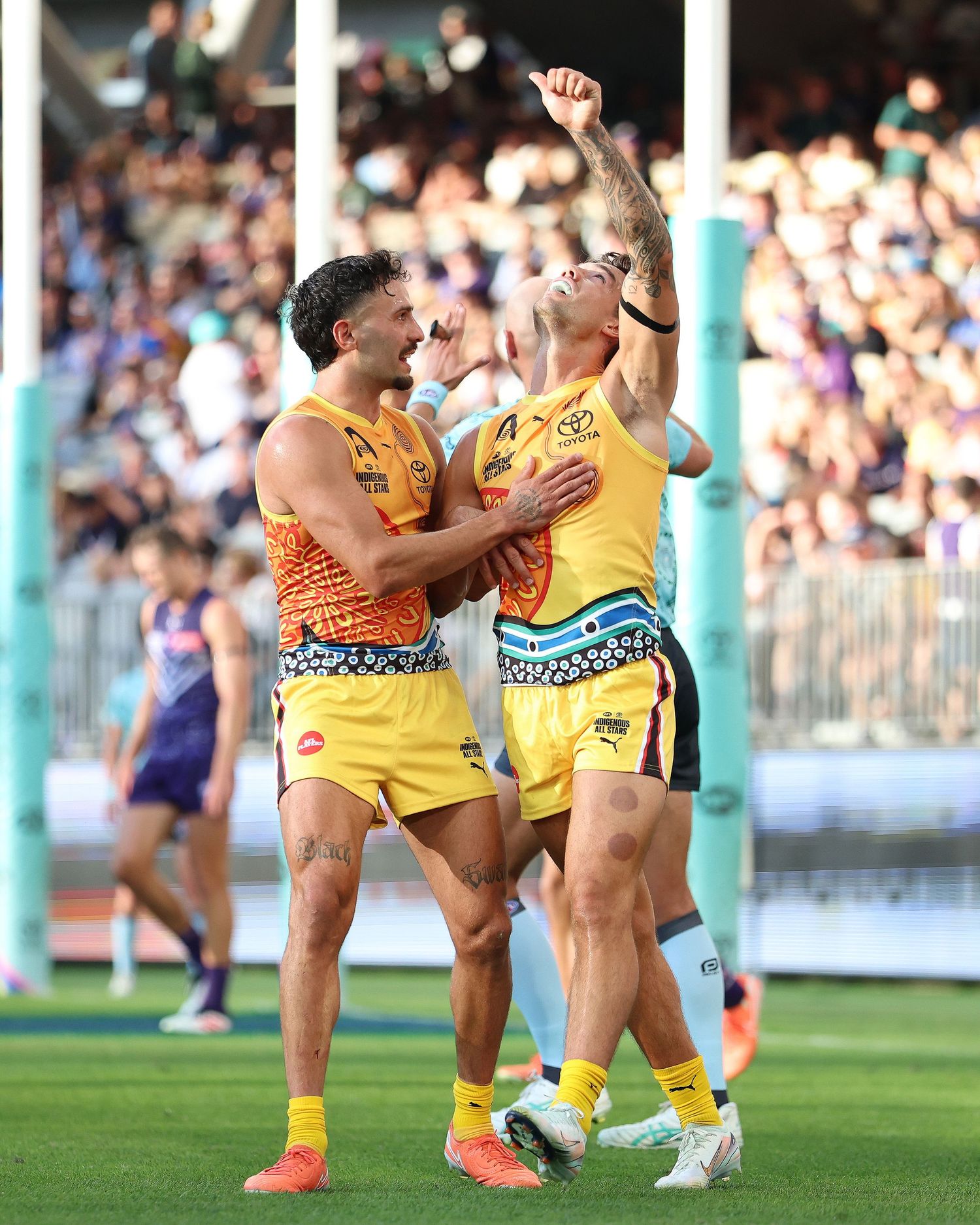 Players in yellow and orange jerseys celebrating during a sports match.