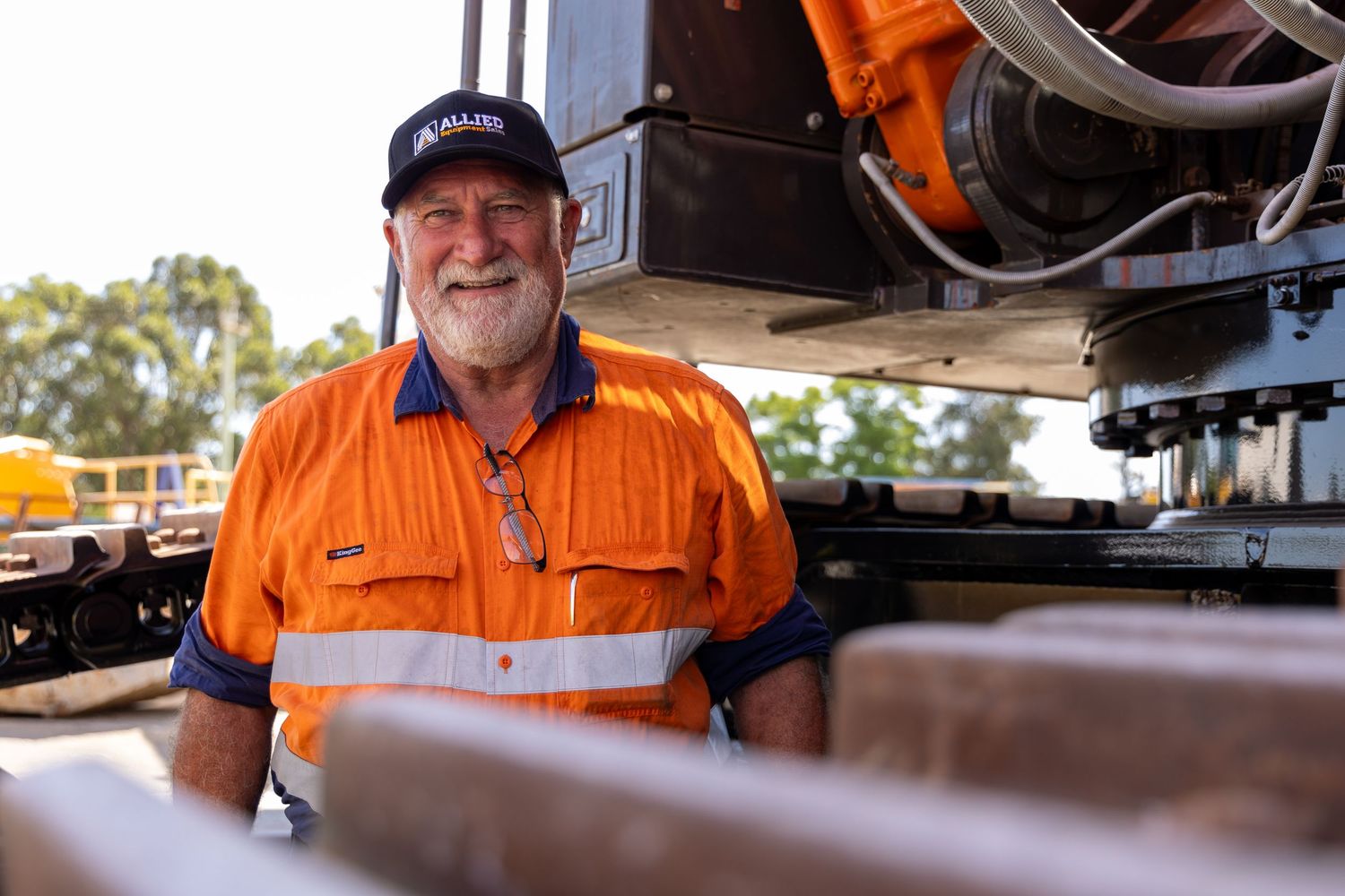 Workers in bright orange safety uniforms are performing maintenance on industrial equipment and machinery.