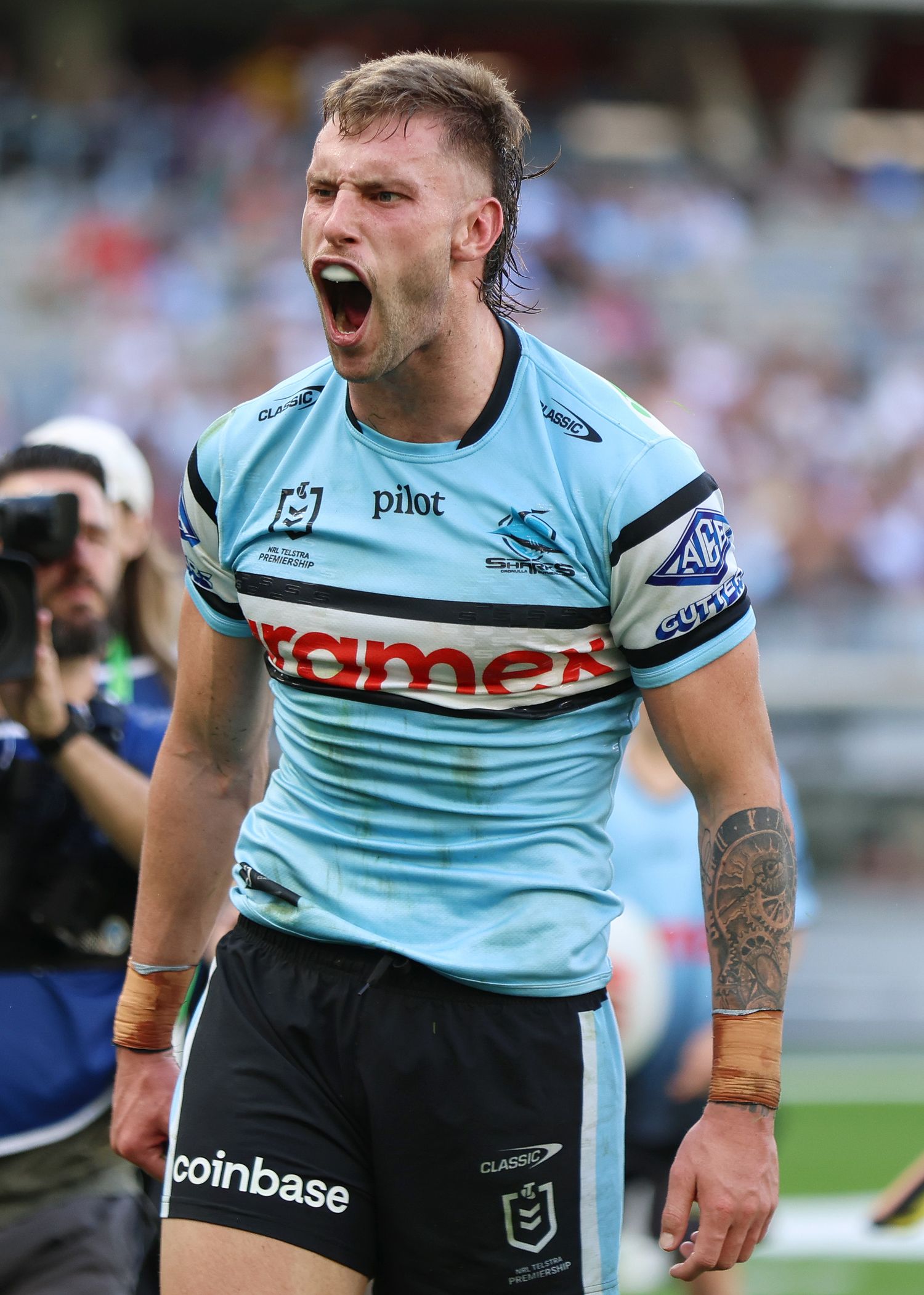 Cronulla Sharks player celebrates intensely while wearing light blue jersey on game day.