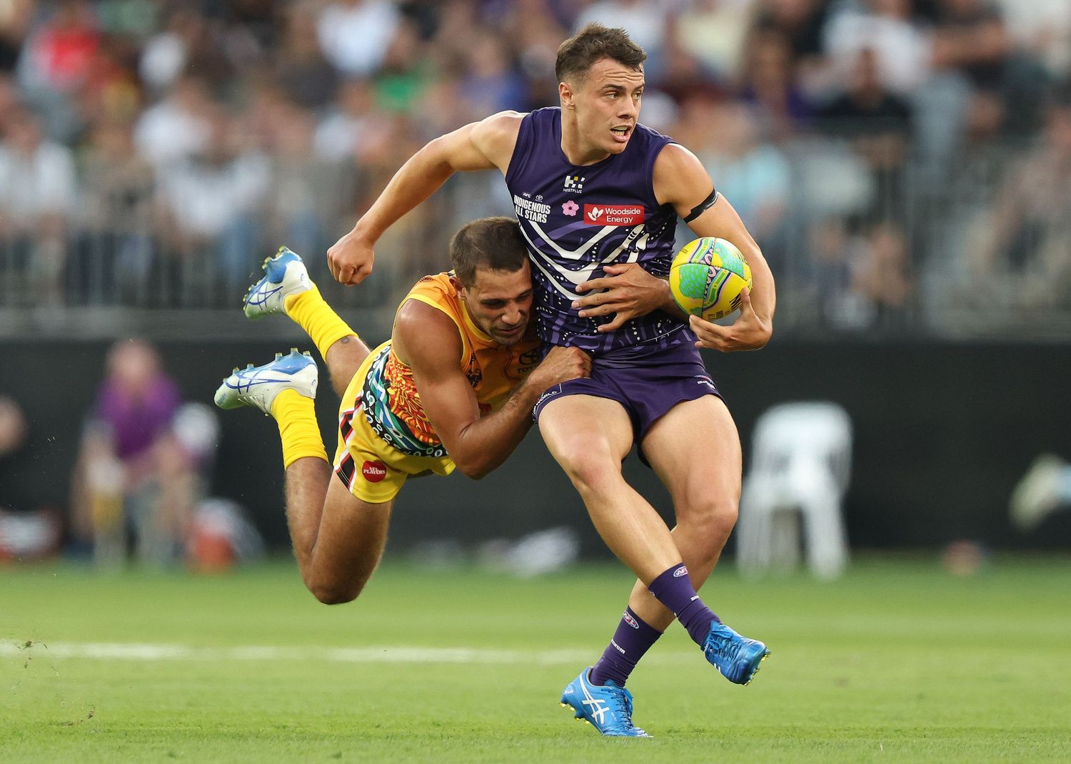 AFL players from opposing teams battle for possession of the ball during an intense match moment.