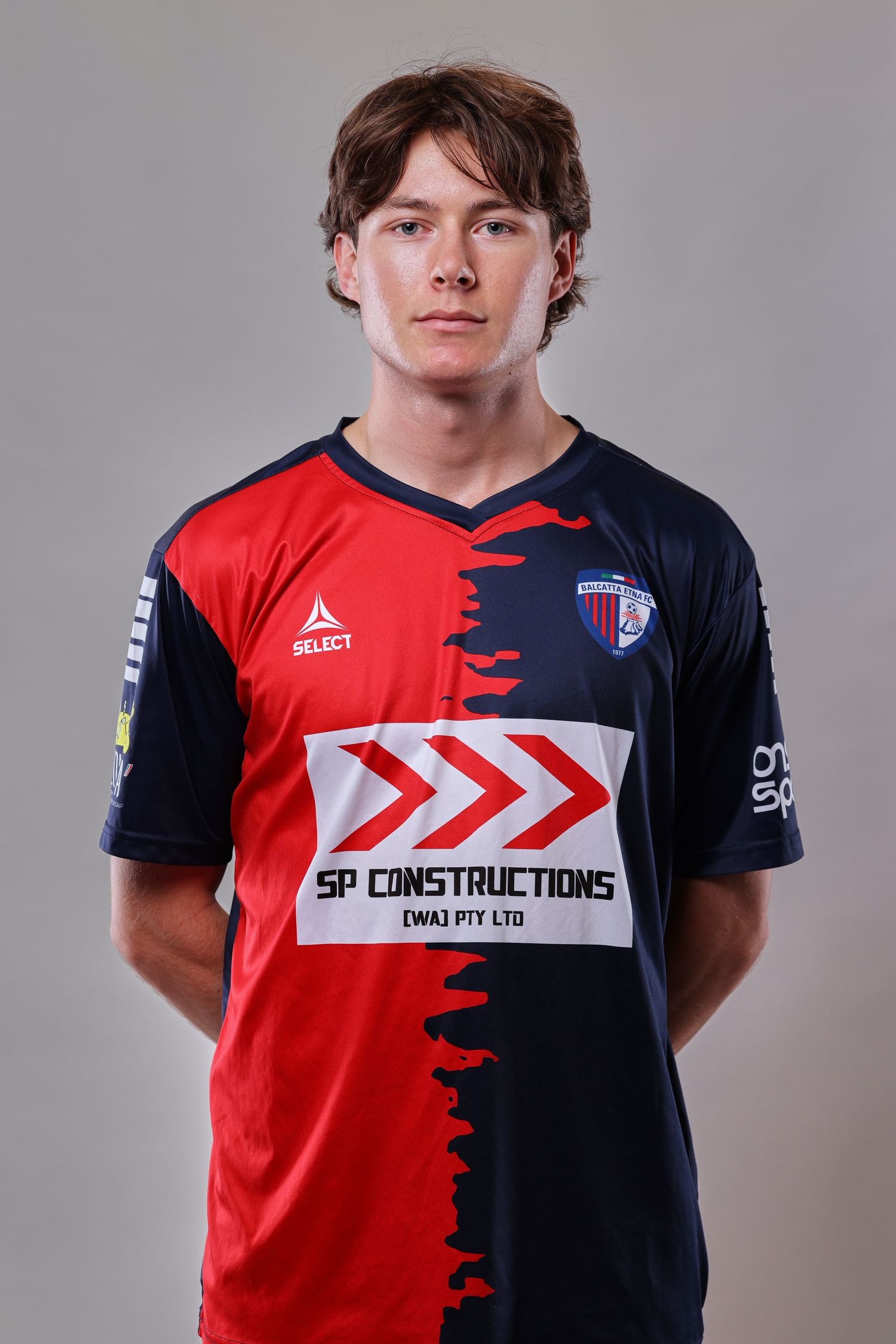 Athletic uniform design featuring split red and navy colors with white geometric accents and sponsor logos.