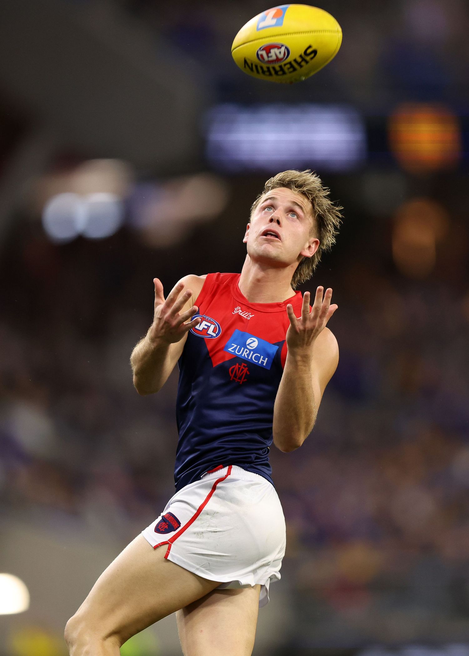 Player attempts to mark the ball during an AFL match at night.