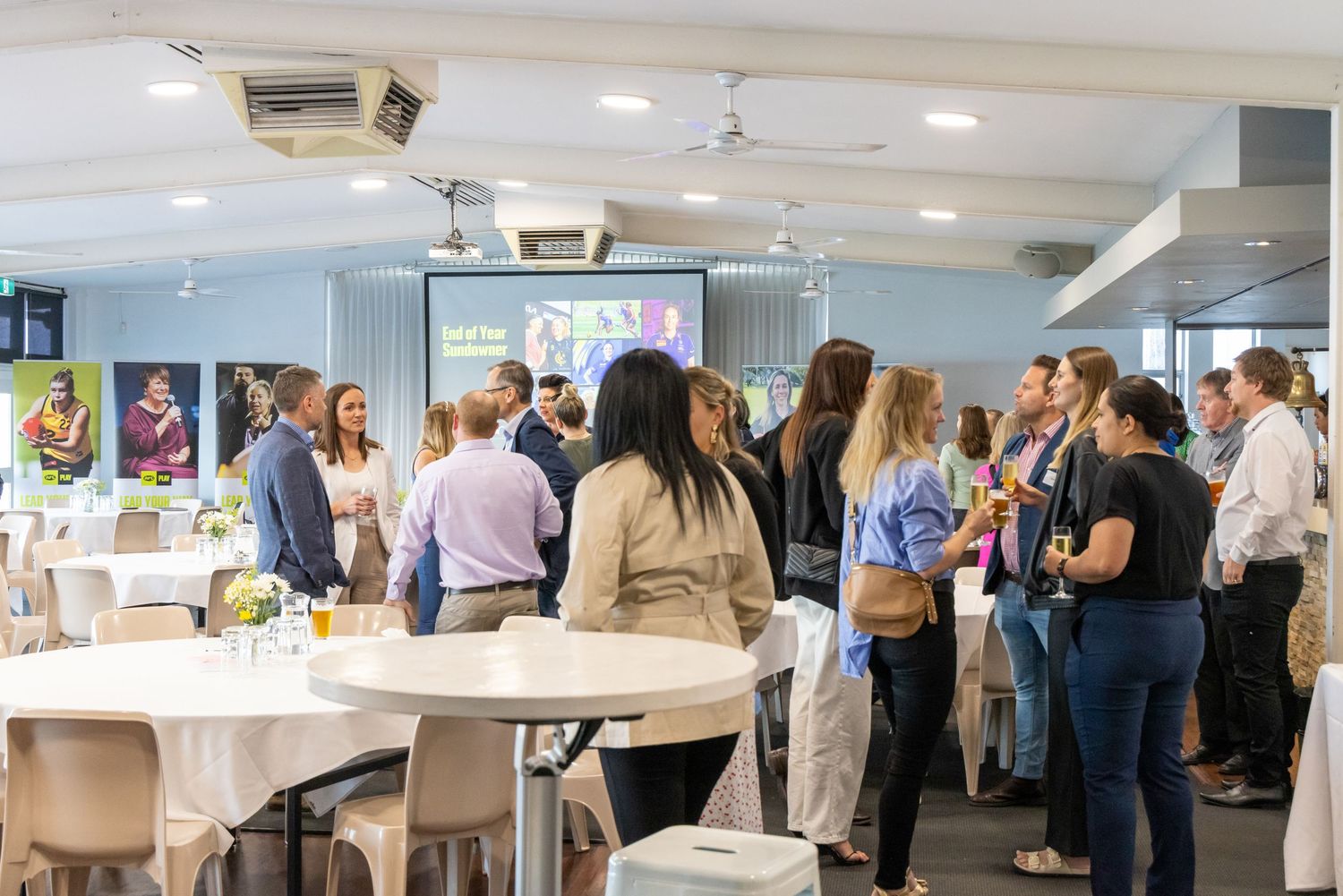 Networking event in modern office space with people mingling around round tables.