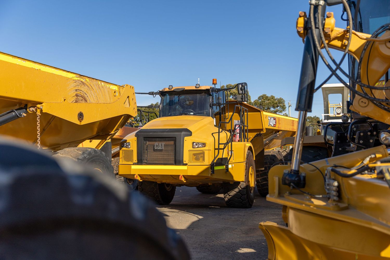 Yellow industrial dump trucks and construction equipment parked in outdoor heavy machinery lot.