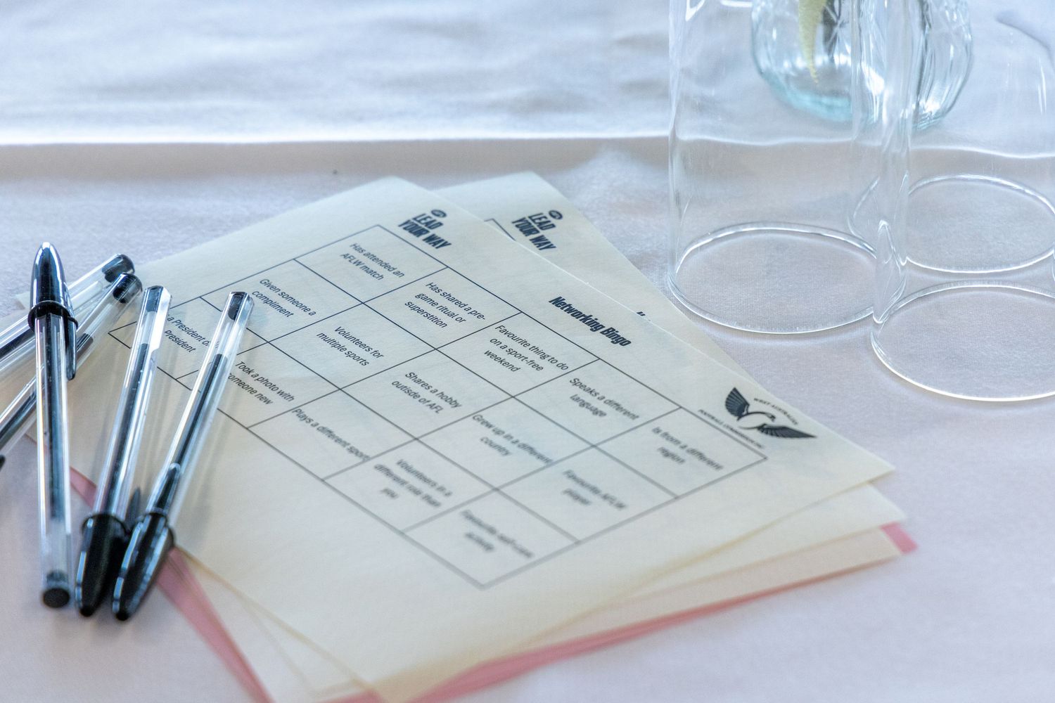 Business meeting materials with pens and paperwork on white table.