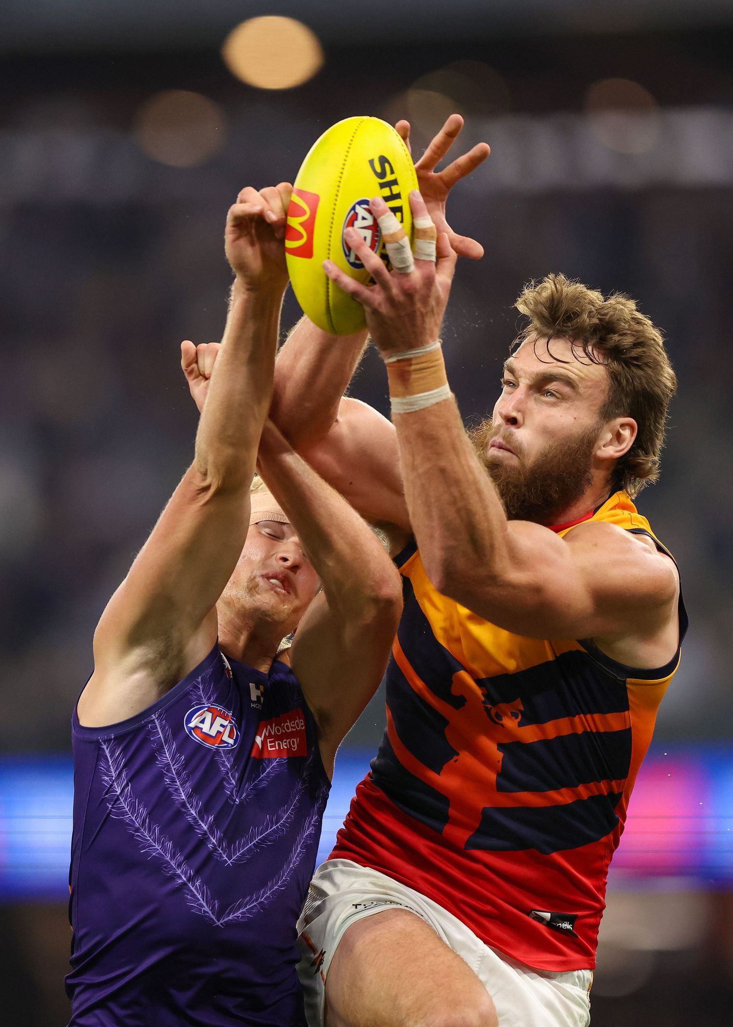 Players from opposing teams jump and battle for possession of the yellow football.