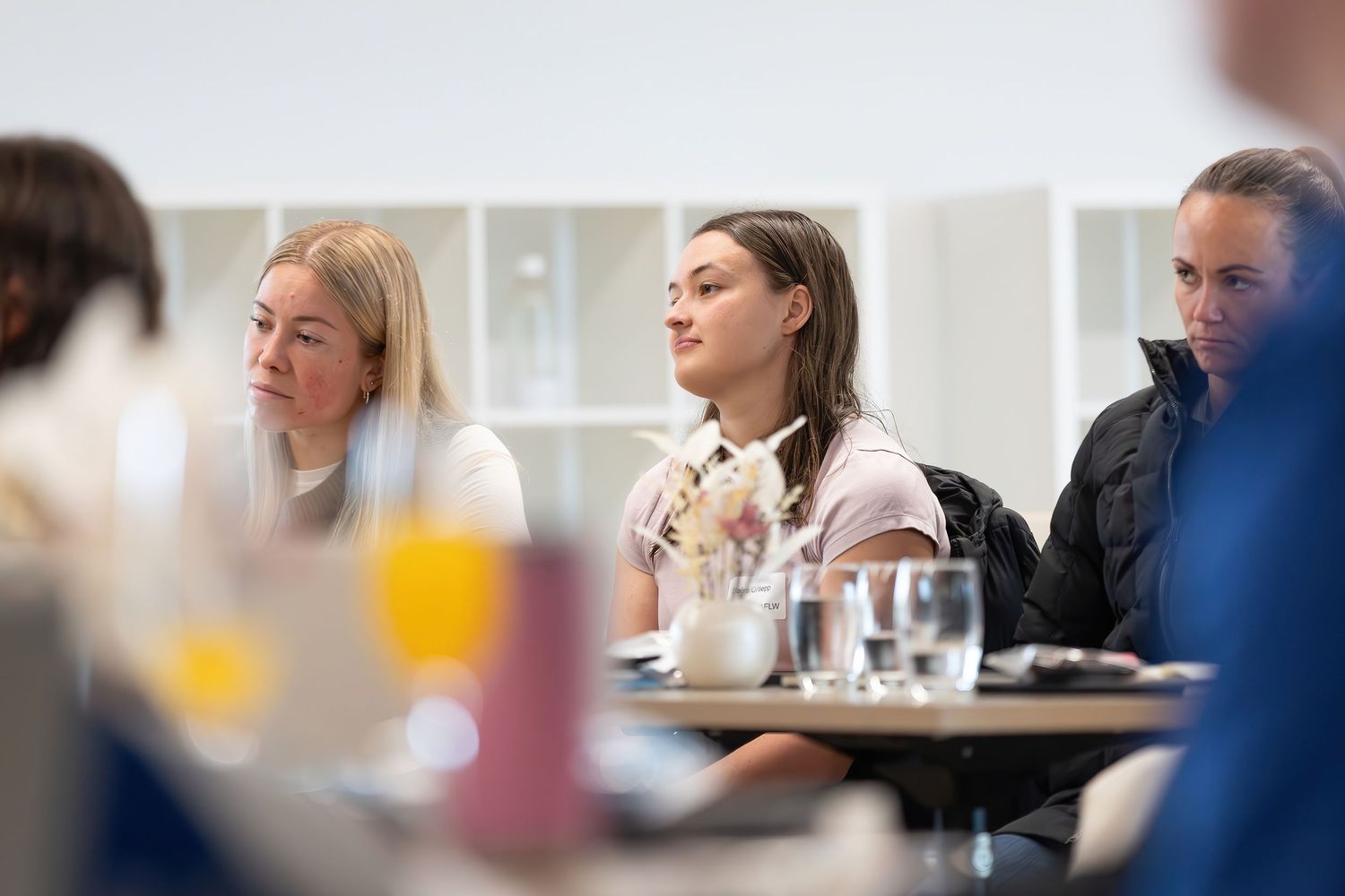 People listening attentively during a business meeting or training session with glasses of water and beverages on table.