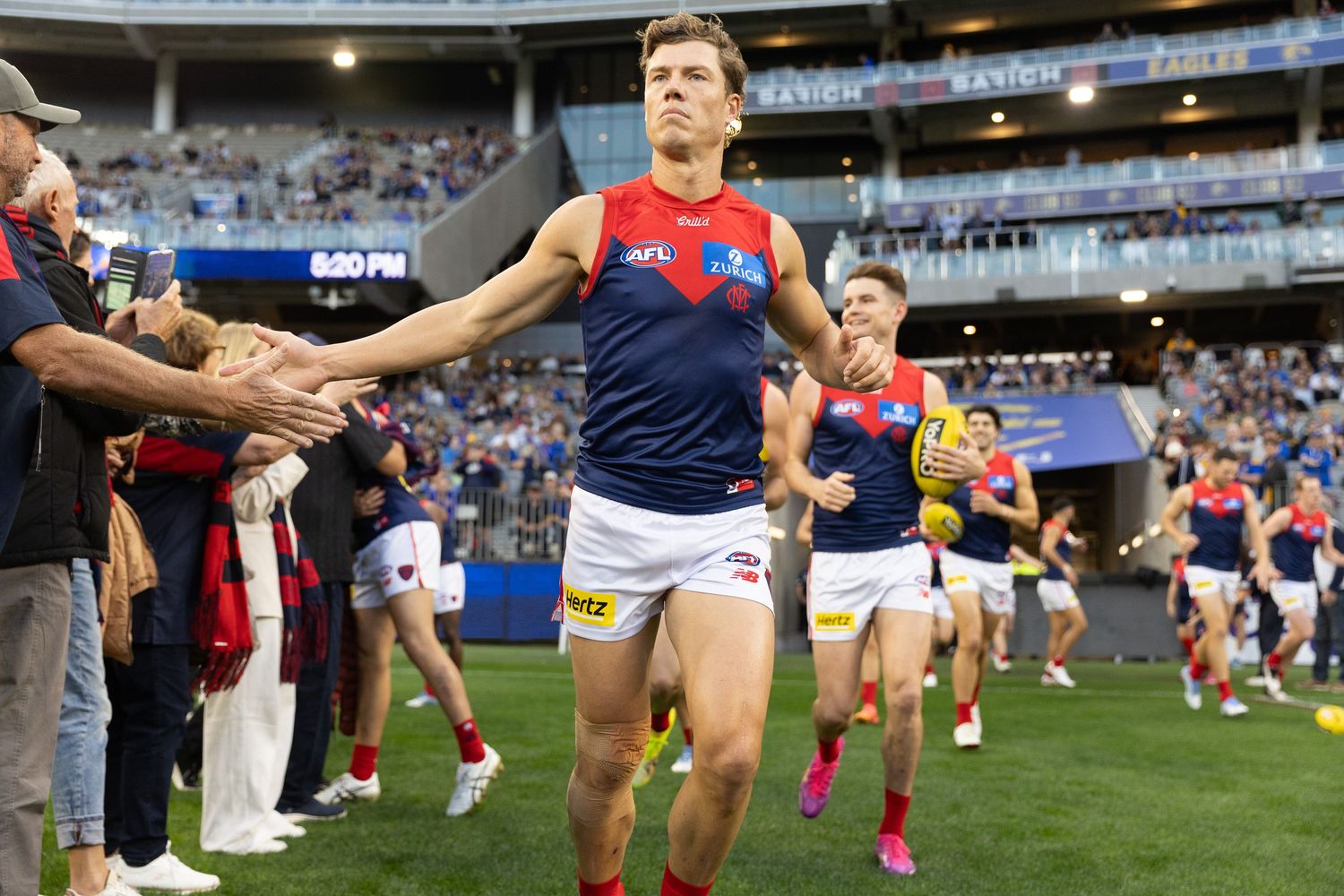 AFL player high-fives fans while walking off the field after the game.